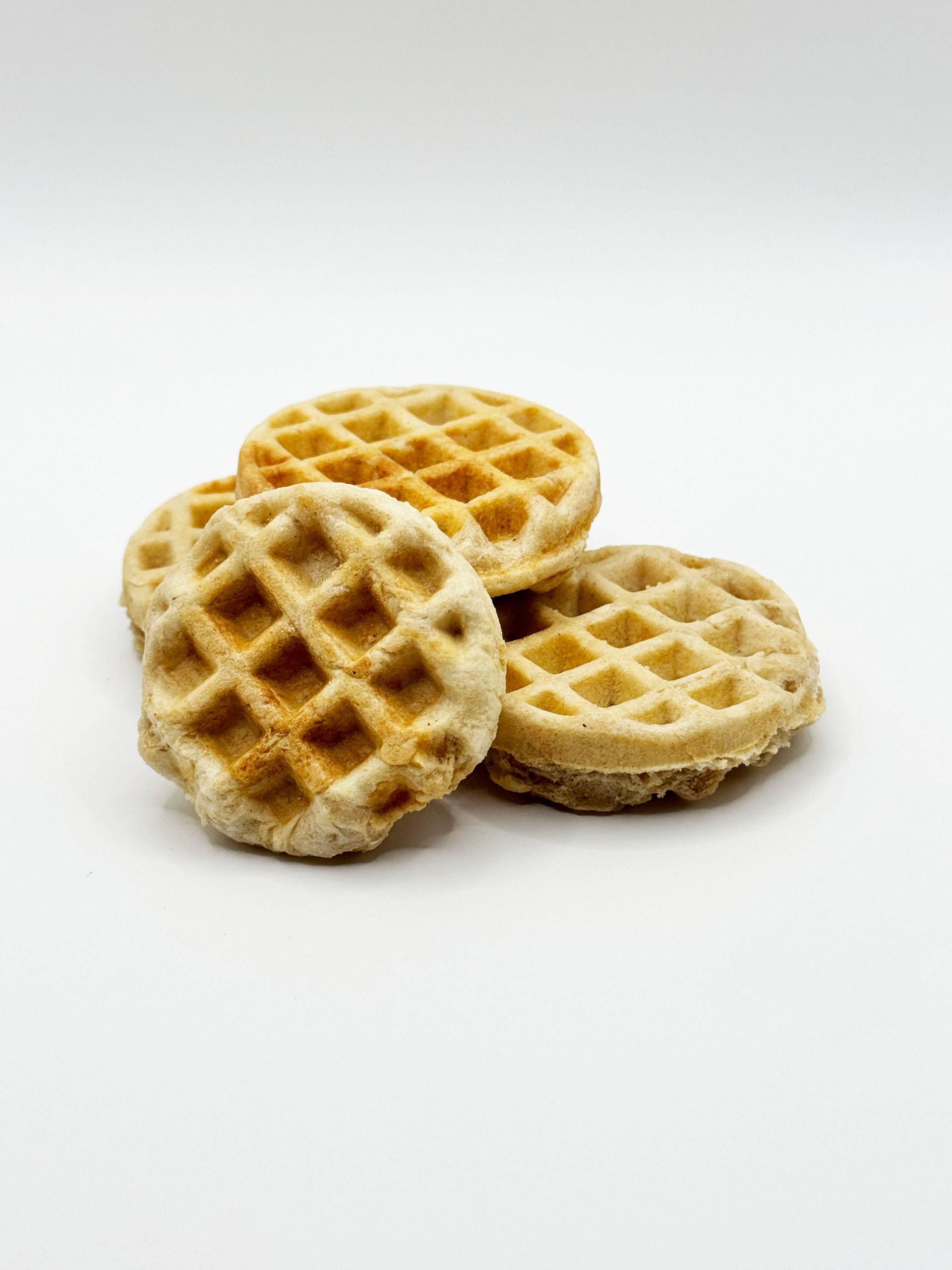 Three waffles are stacked on top of each other on a white surface.