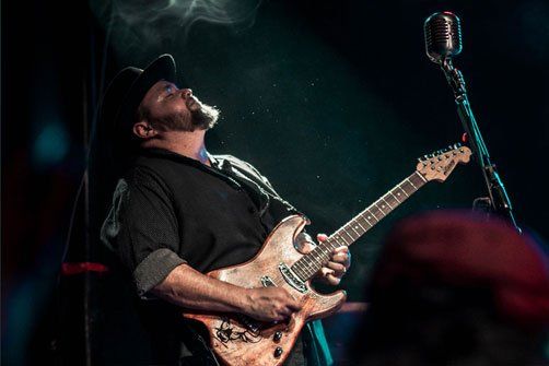 Image may contain guitar, carbon microphone, hat, may playing guitar, smoke