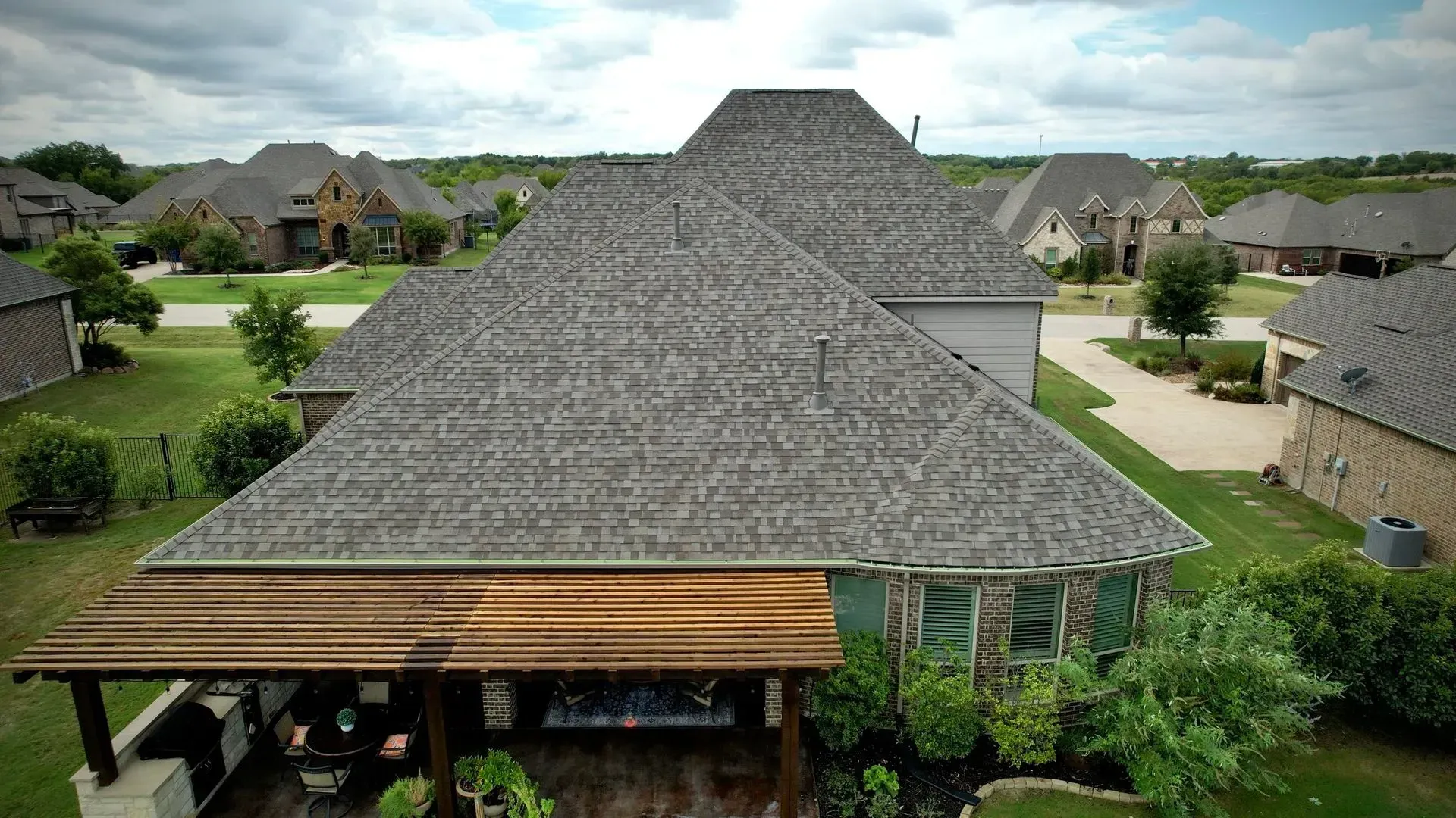 An aerial view of a house with a large roof in a residential area.