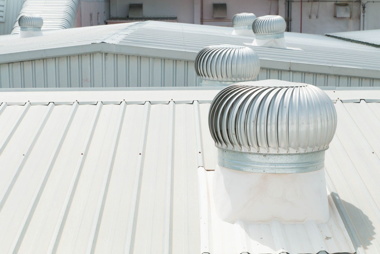 A white roof with a metal fan on top of it.