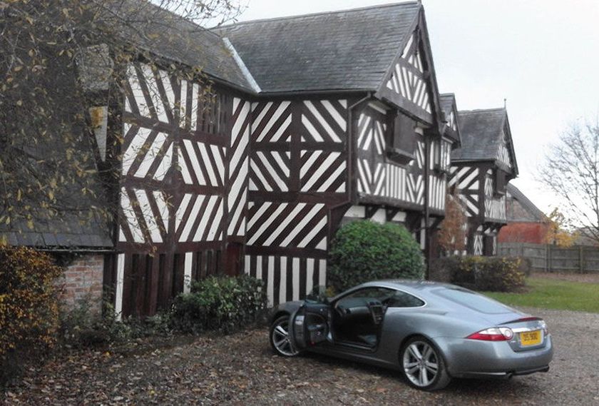 A car is parked in front of a house with the door open.