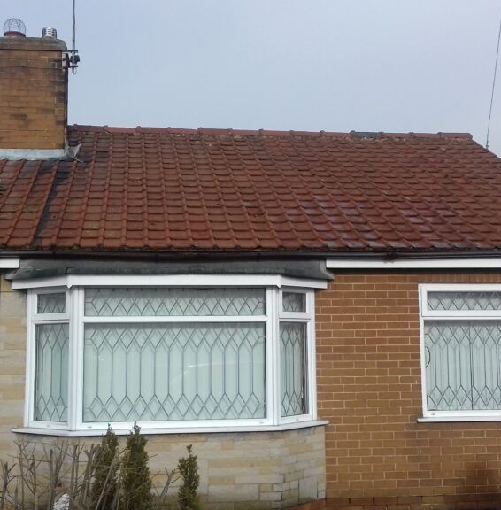 A brick house with a tiled roof and two windows.