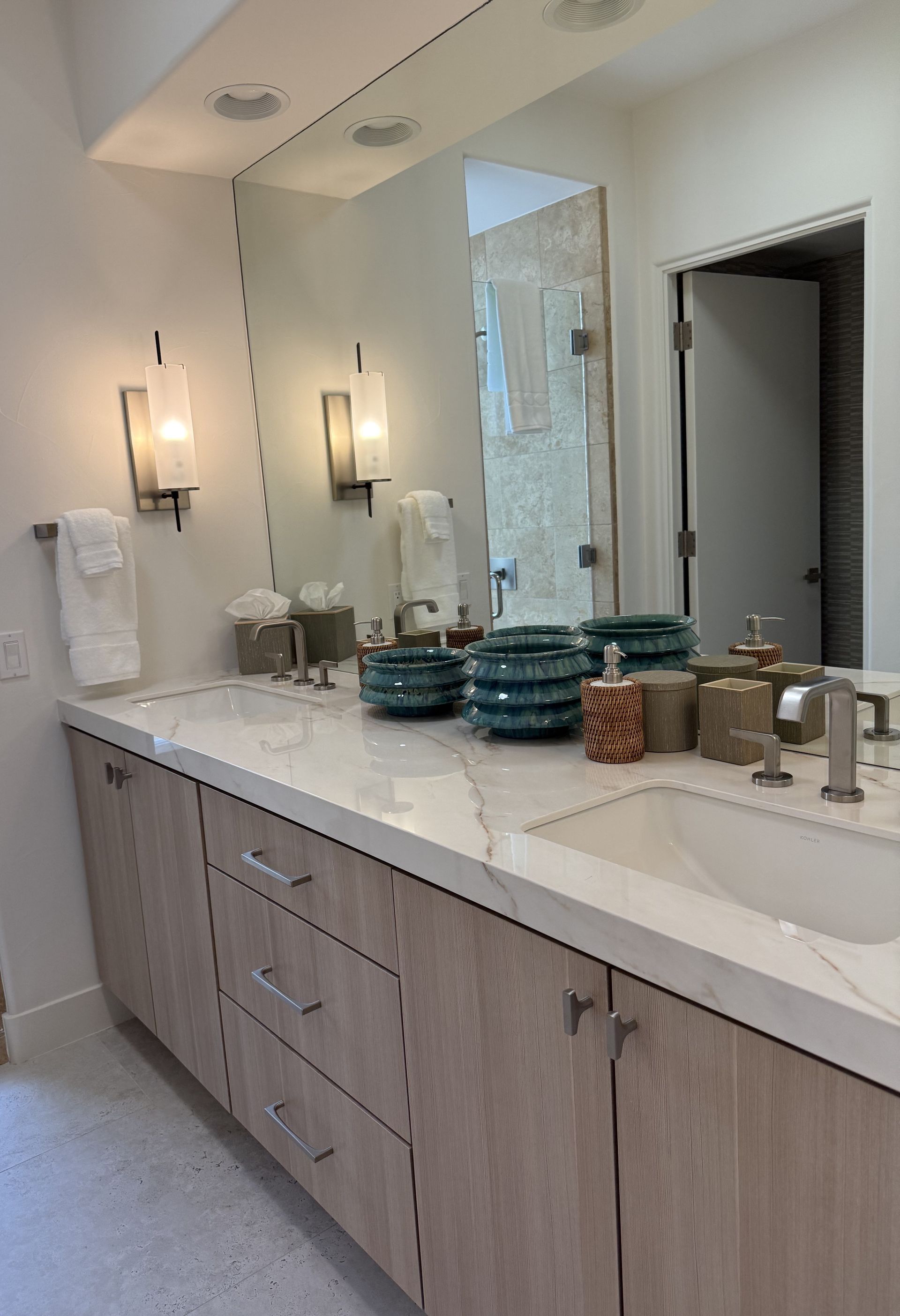 Plumber in blue overalls and a cap fixing a kitchen faucet, with a toolbox nearby.