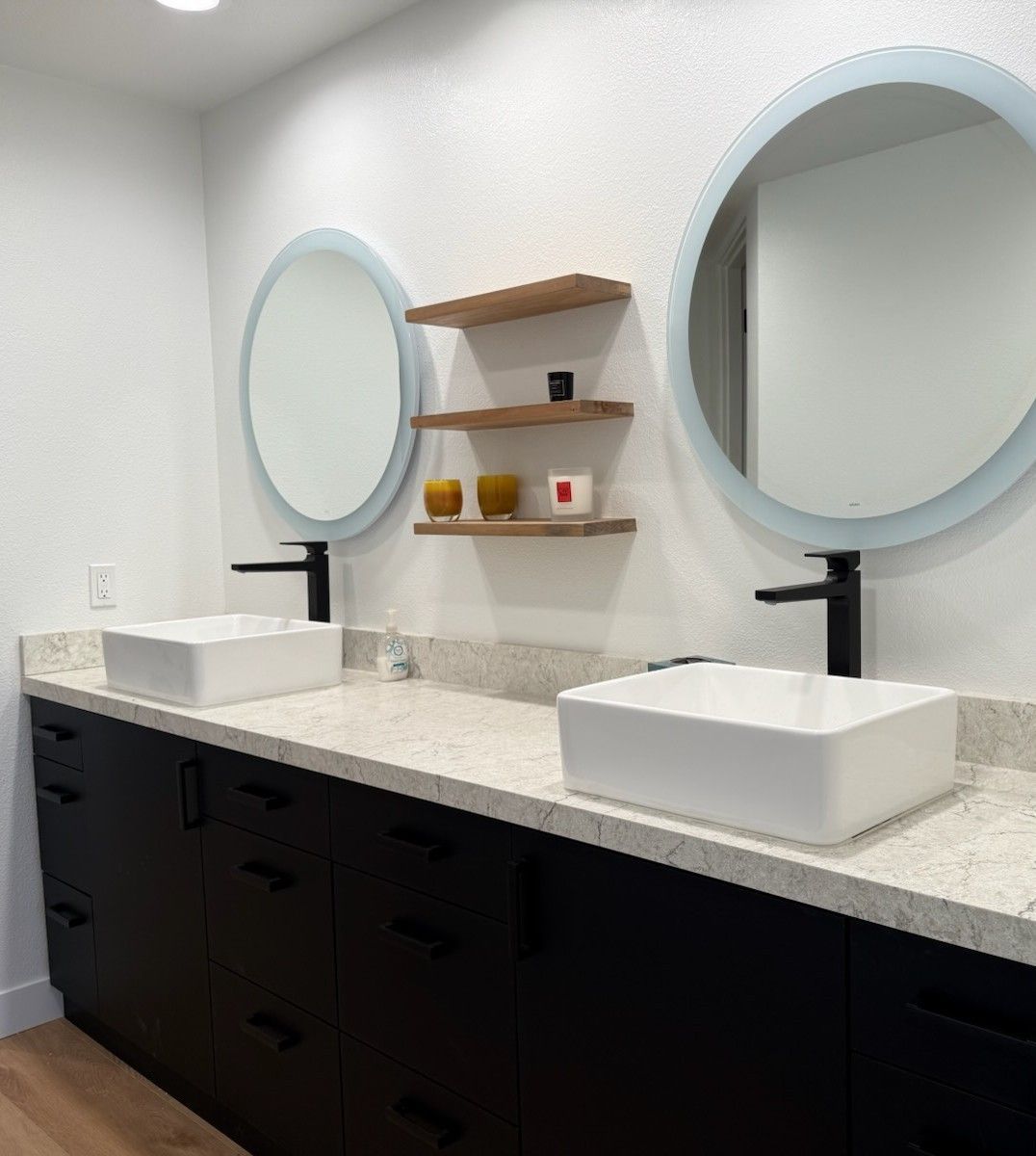 Plumber in blue work clothes, orange gloves, and tool belt, fixing a white sink in a bathroom.