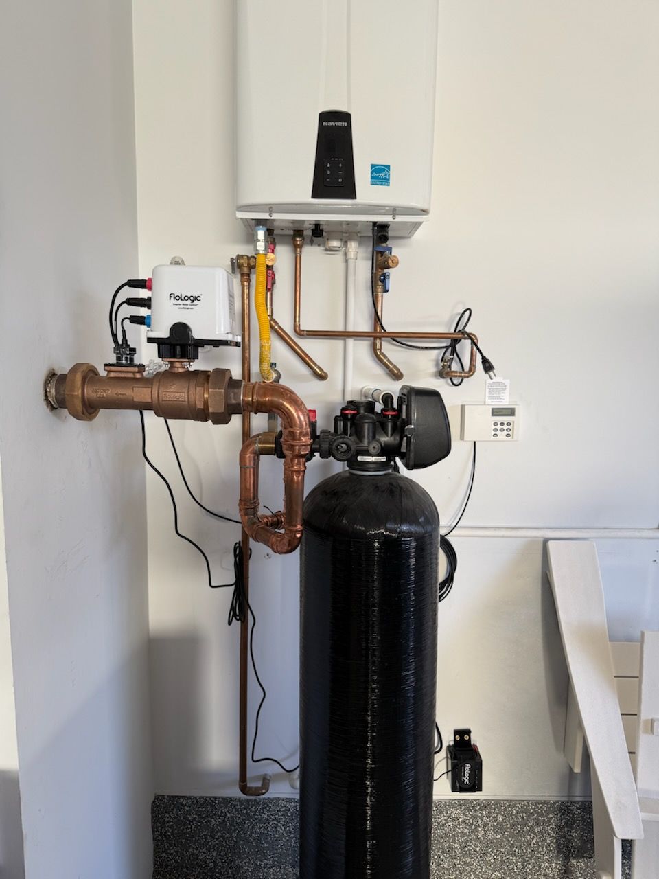 Two smiling repairmen in work uniforms stand near the open back of a service van filled with tools.