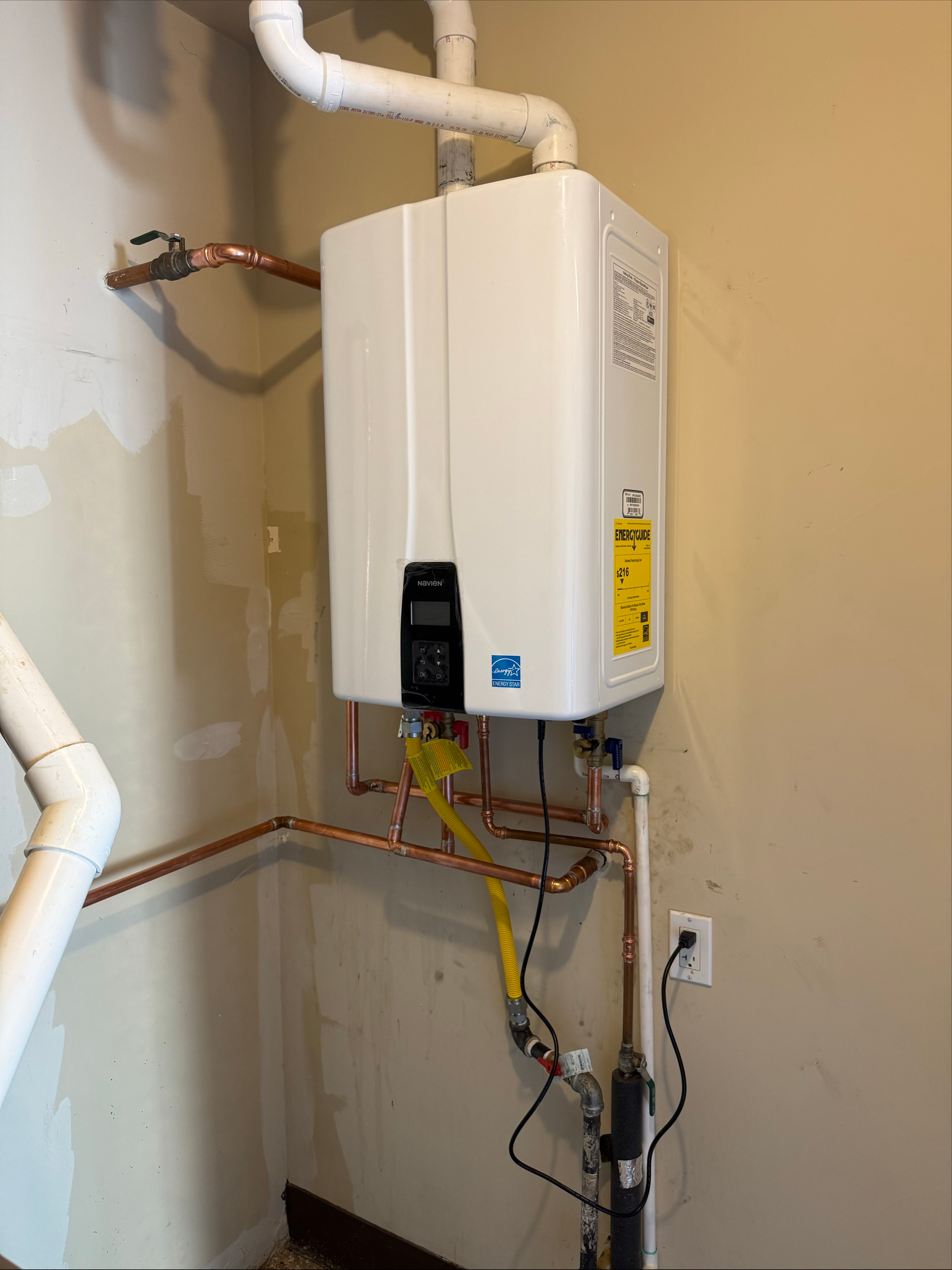 Man in plaid shirt repairs a water heater with pliers, indoors.