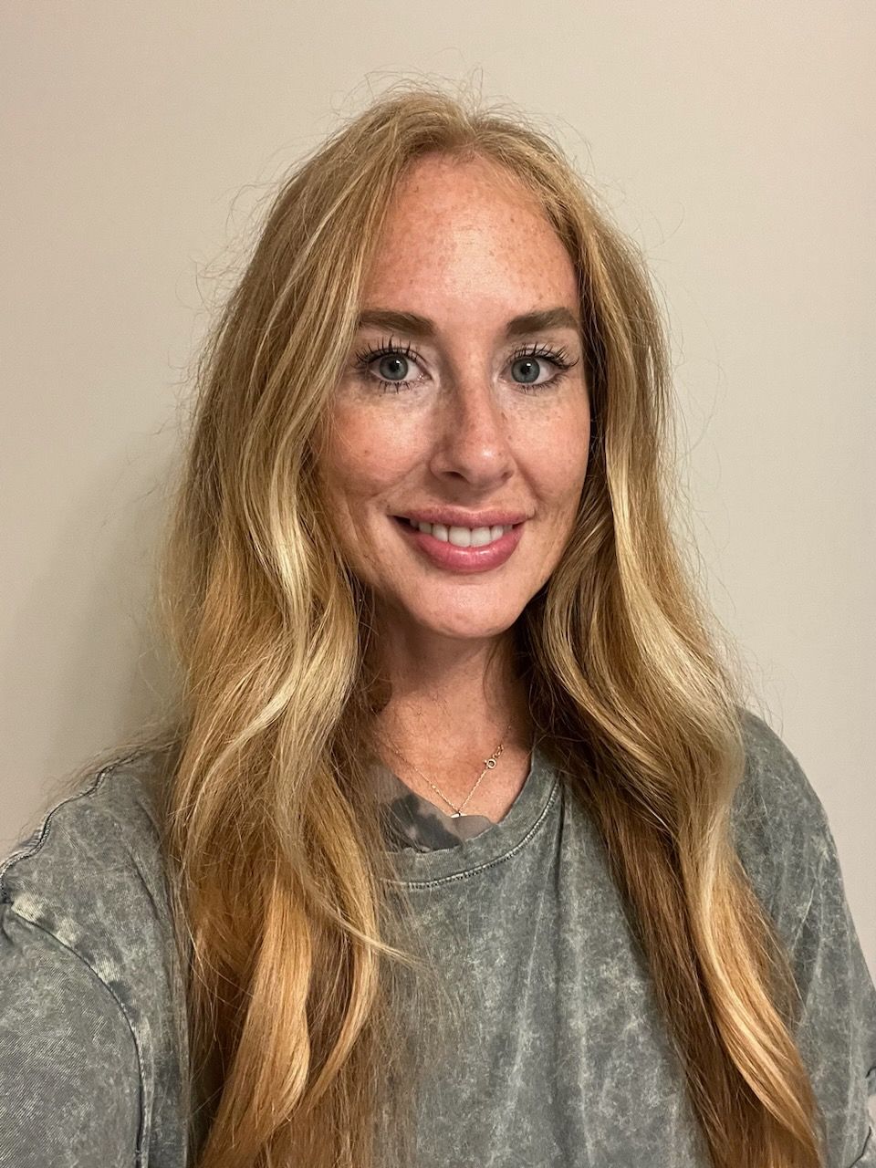 A woman with long blonde hair and freckles is smiling for the camera.