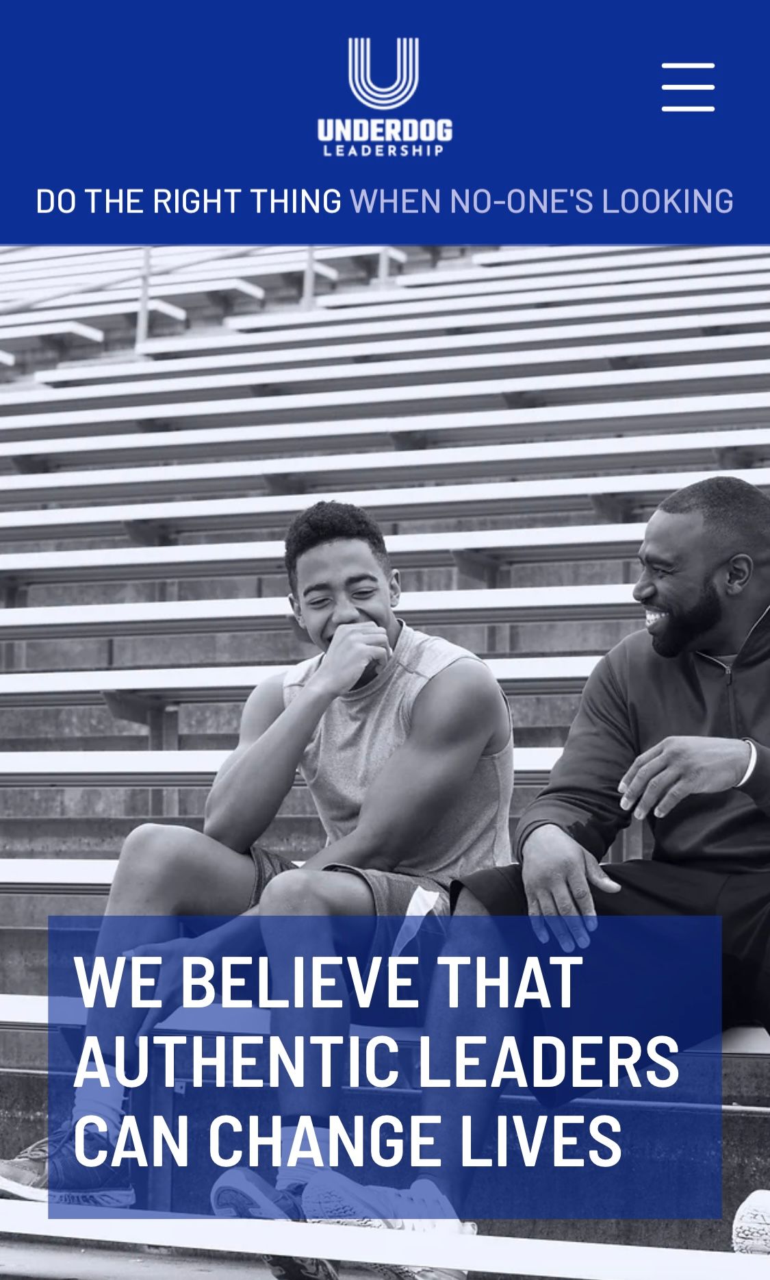 Younger man and older man sharing a joke sitting on bench seats in a sports stadium