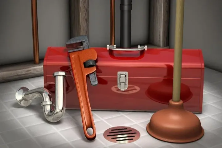 Plumbing tools on tile: red toolbox, wrench, plunger, pipe, and drain cover. Plumbing tools on tile: red toolbox, wrench, plunger, pipe, and drain cover.