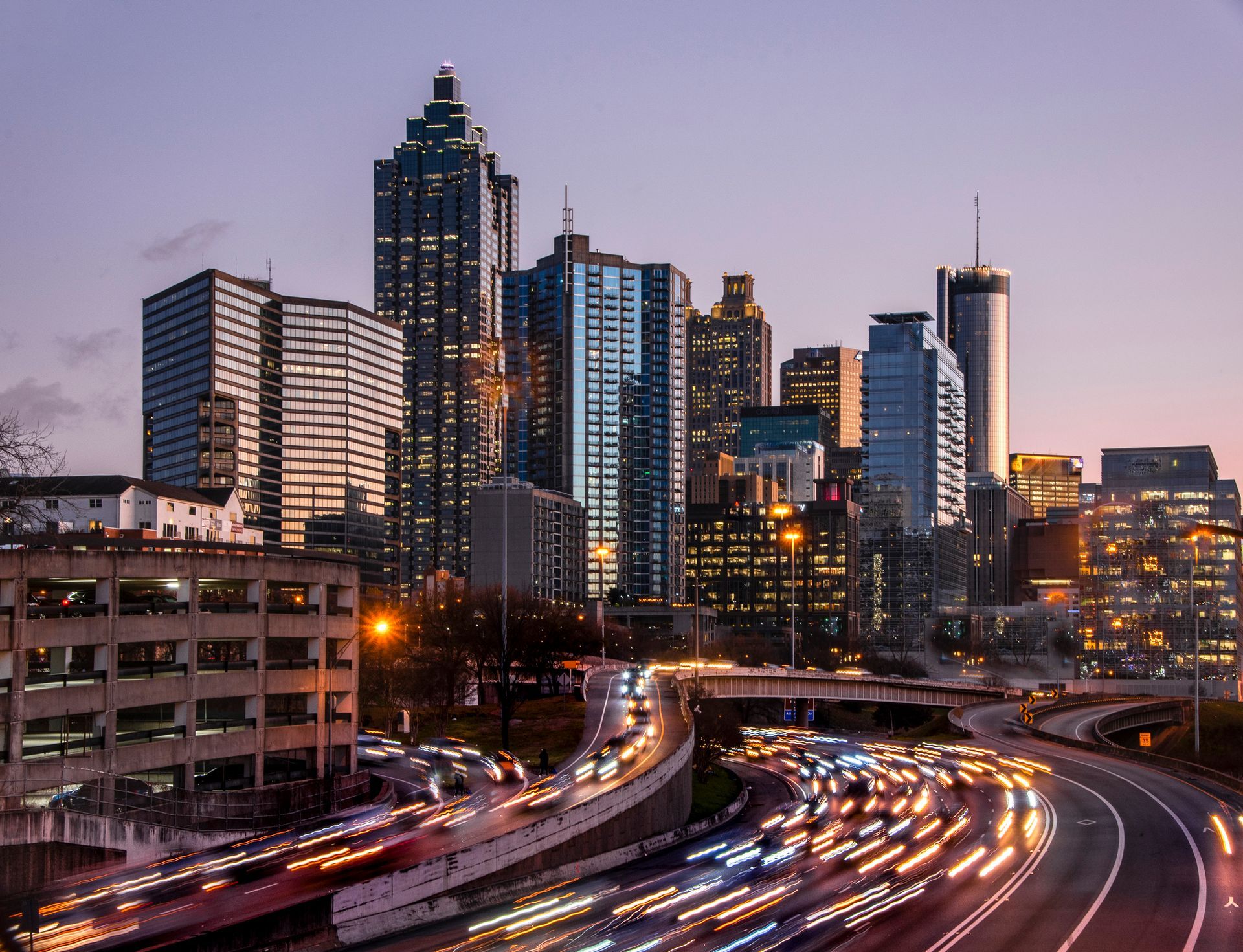Atlanta skyline at dusk with traffic trails on highway below.