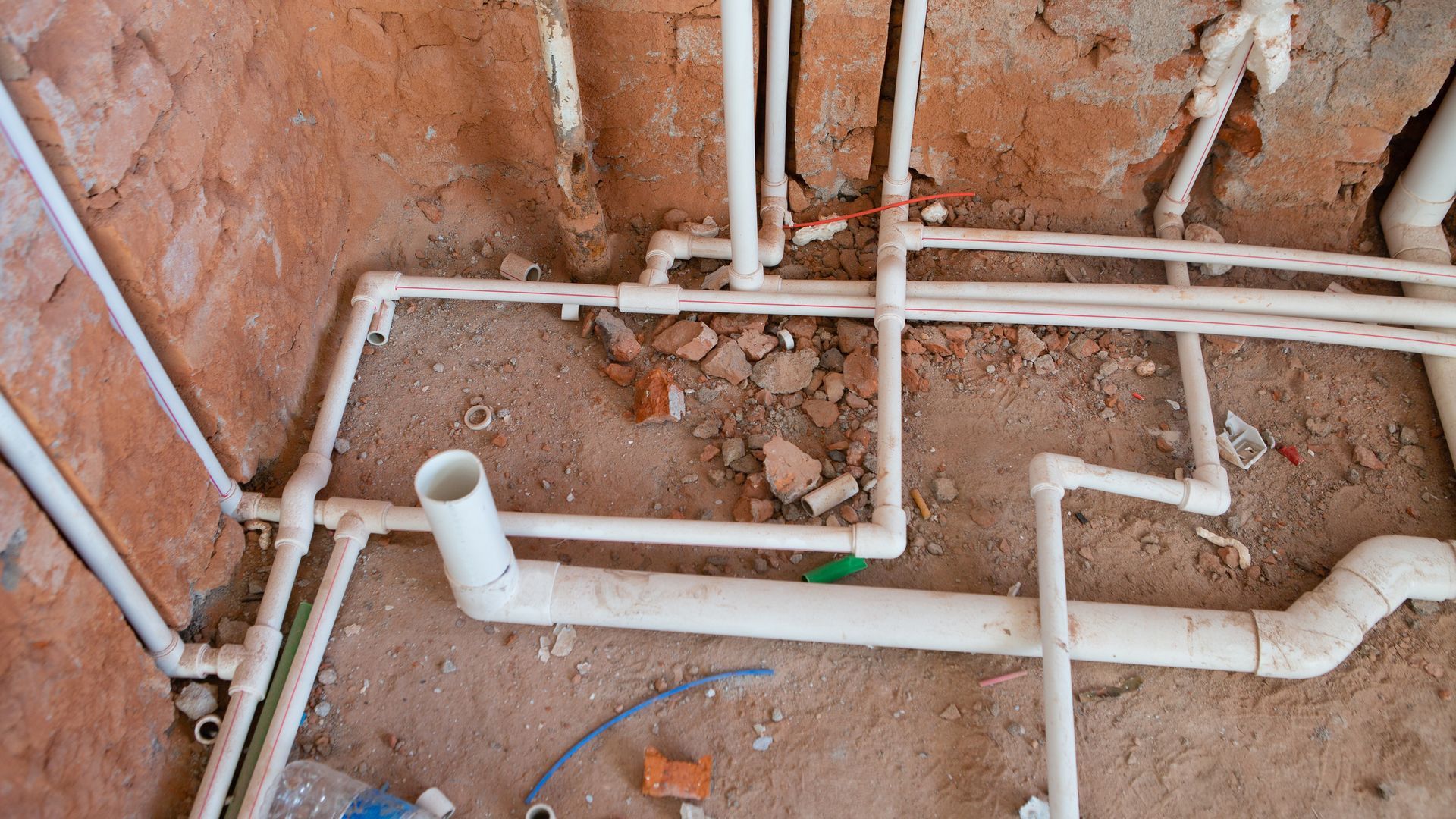White PVC pipes in a brick wall, part of a plumbing installation.