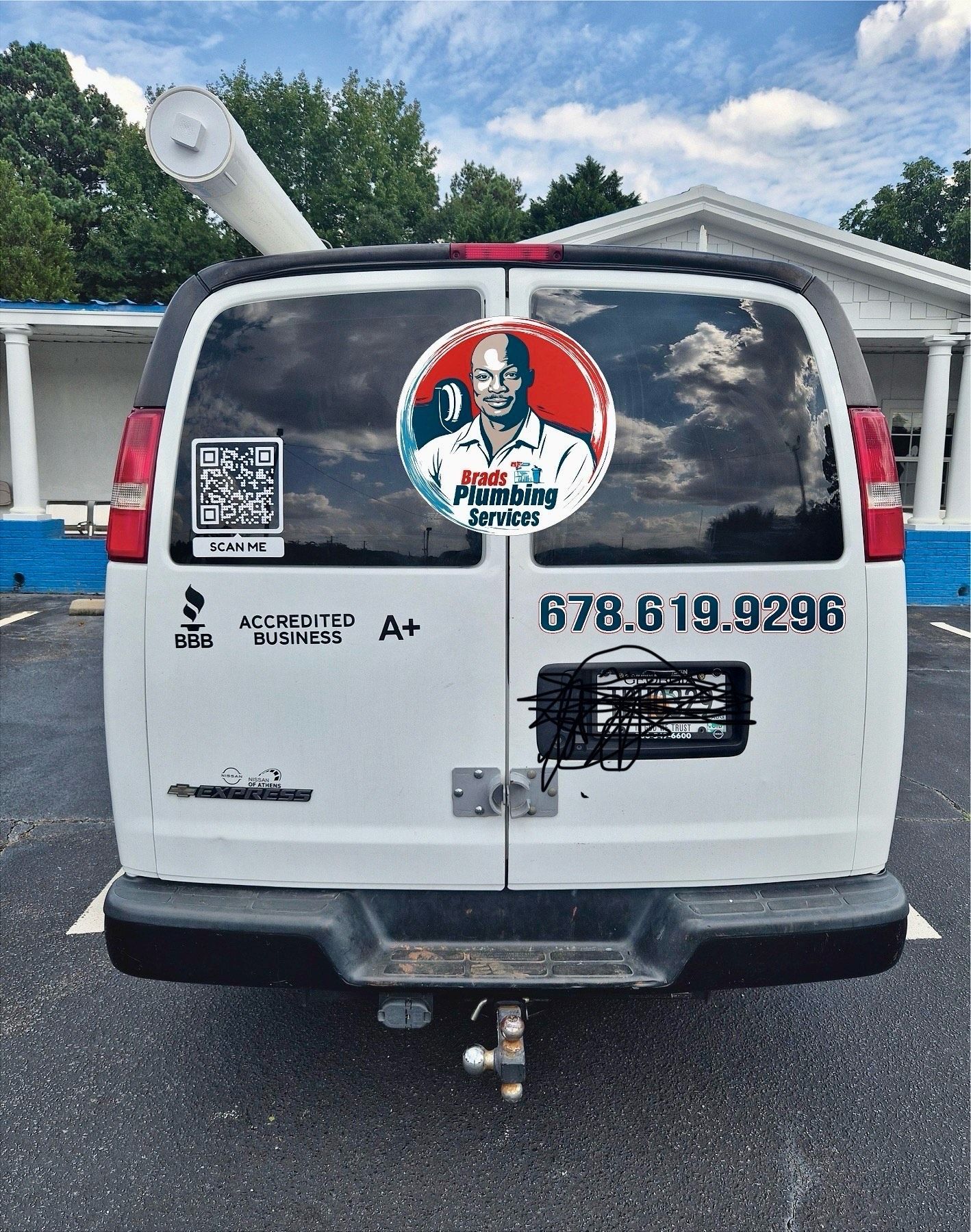 White van with business logo and phone number, parked.
