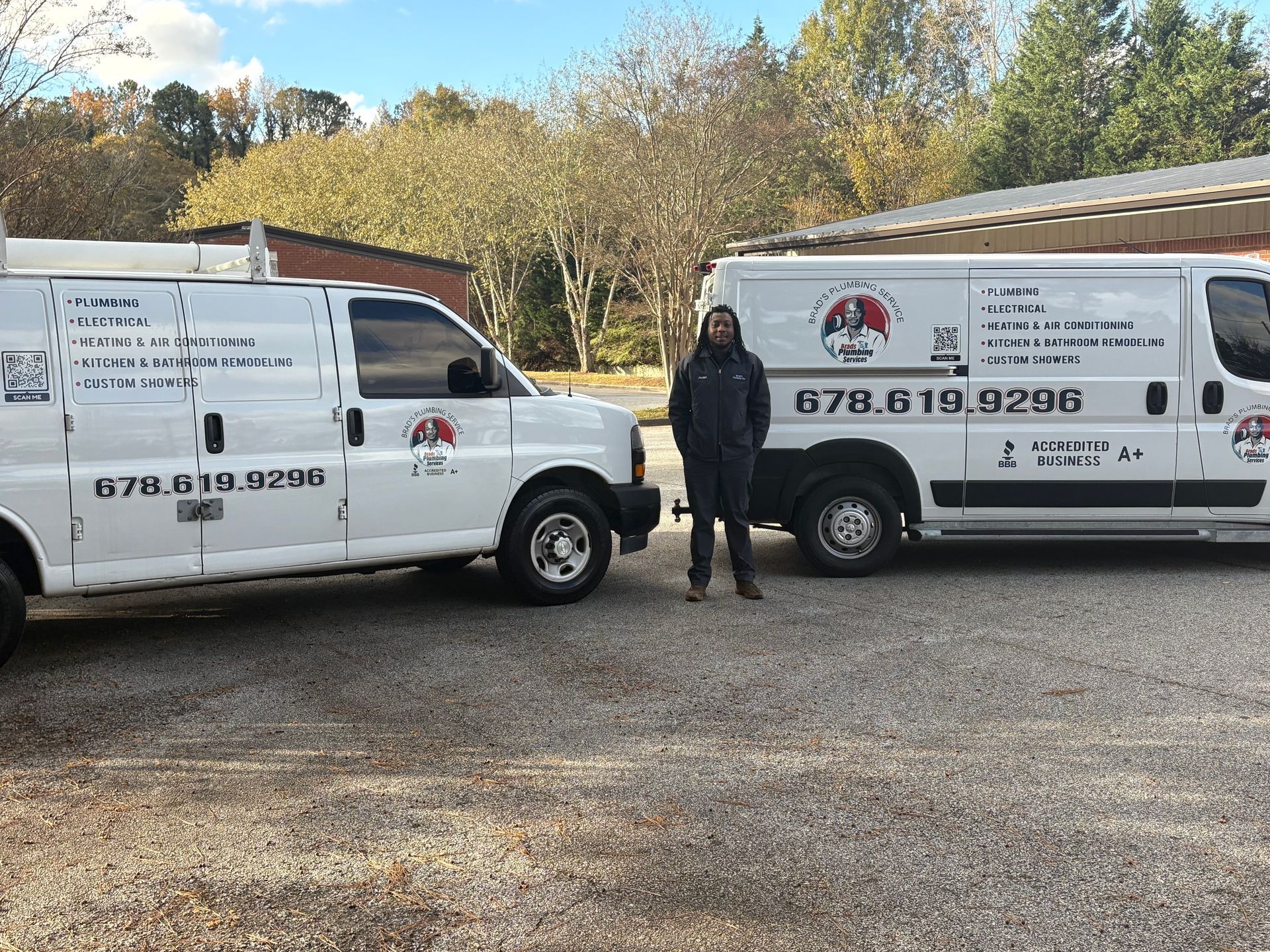 Person standing between two white service vans, likely for a business, parked outside under a clear sky.