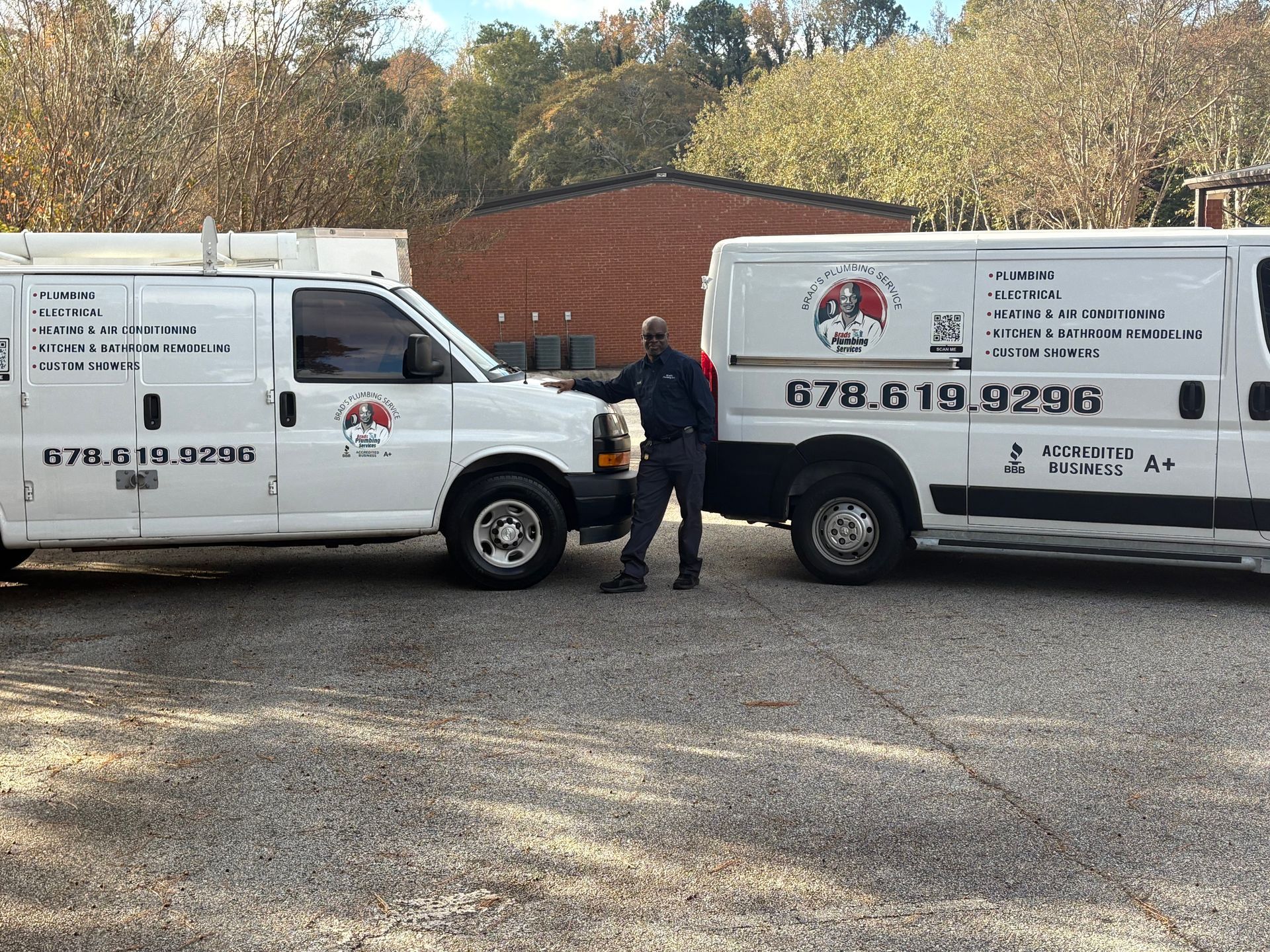 Two white vans with business logos parked outdoors. A person stands between them.