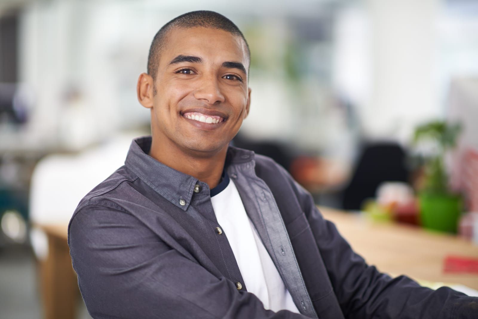 A young man is smiling for the camera while sitting at a table.