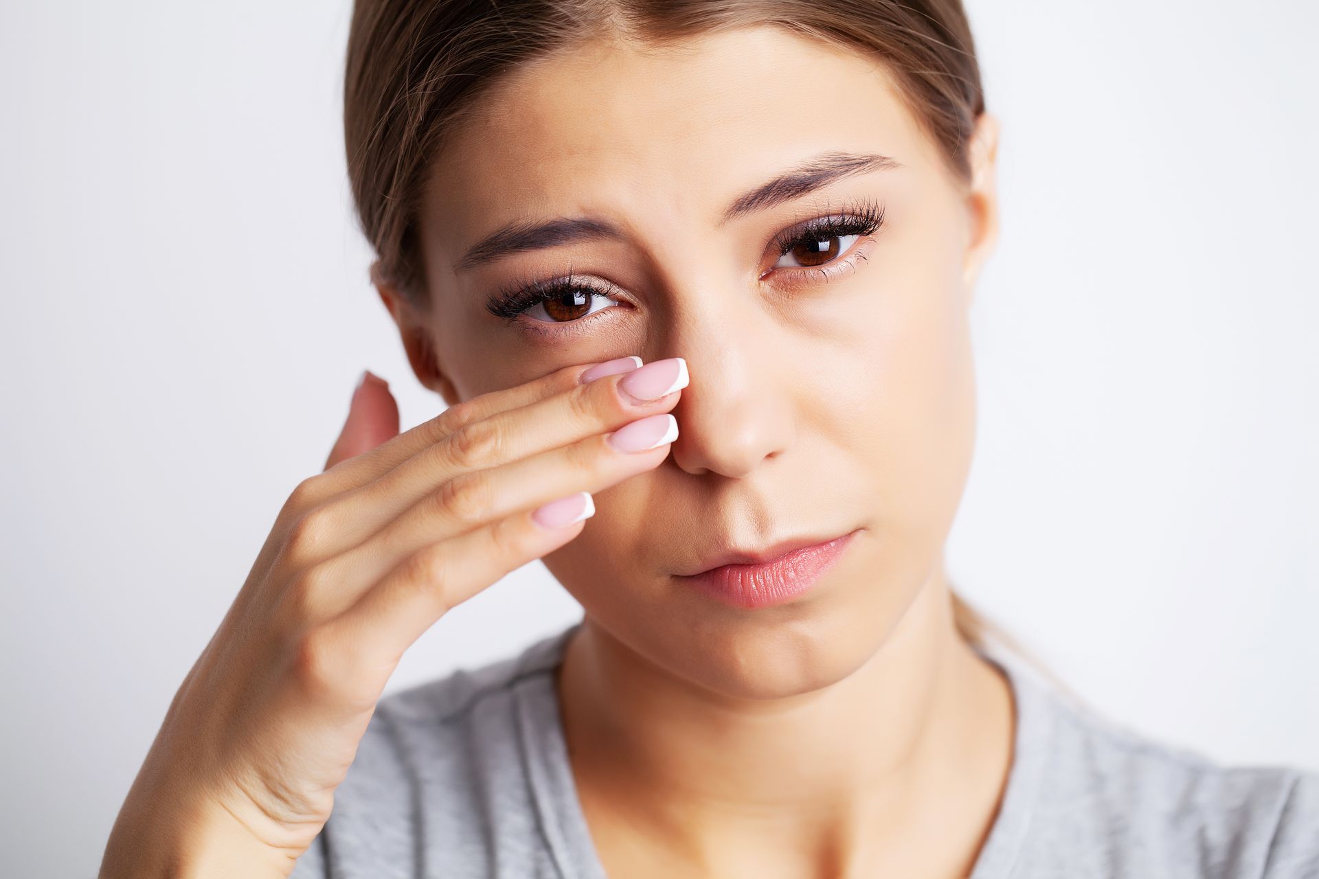 A woman suffering from nasal polyps touching her nose.