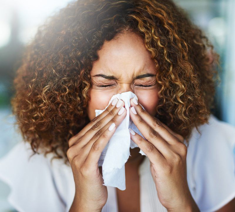 A woman is blowing her nose with a napkin.