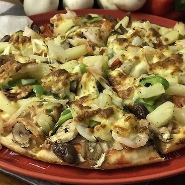 A Pizza With A Lot Of Toppings On It Is On A Red Plate — Bel-Air Pizza In Port Macquarie, NSW