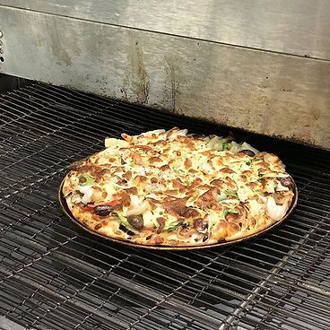 A Pizza Is Sitting On A Wire Rack In A Pizza Oven — Bel-Air Pizza In Port Macquarie, NSW
