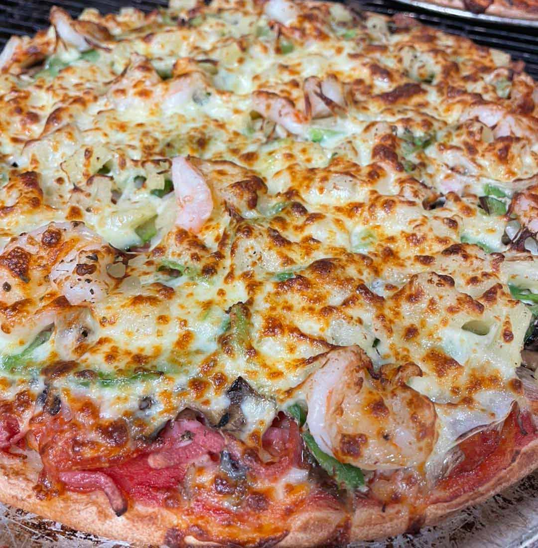 A Pizza With Shrimp, Peppers, Cheese And Tomatoes Is Sitting On A Table — Bel-Air Pizza In Port Macquarie, NSW