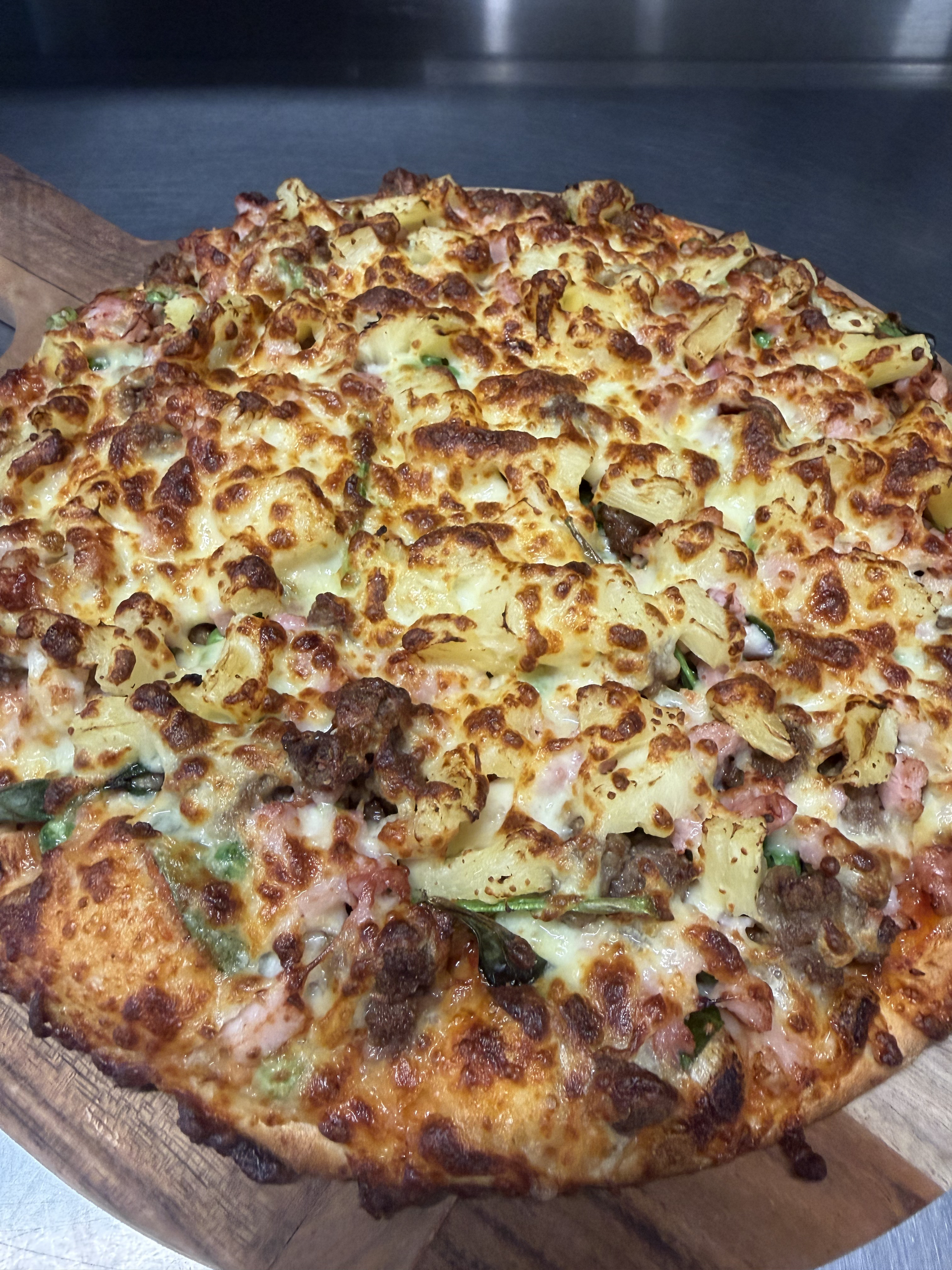 A Pizza Is Being Cooked On A Grill With A Spatula — Bel-Air Pizza In Port Macquarie, NSW