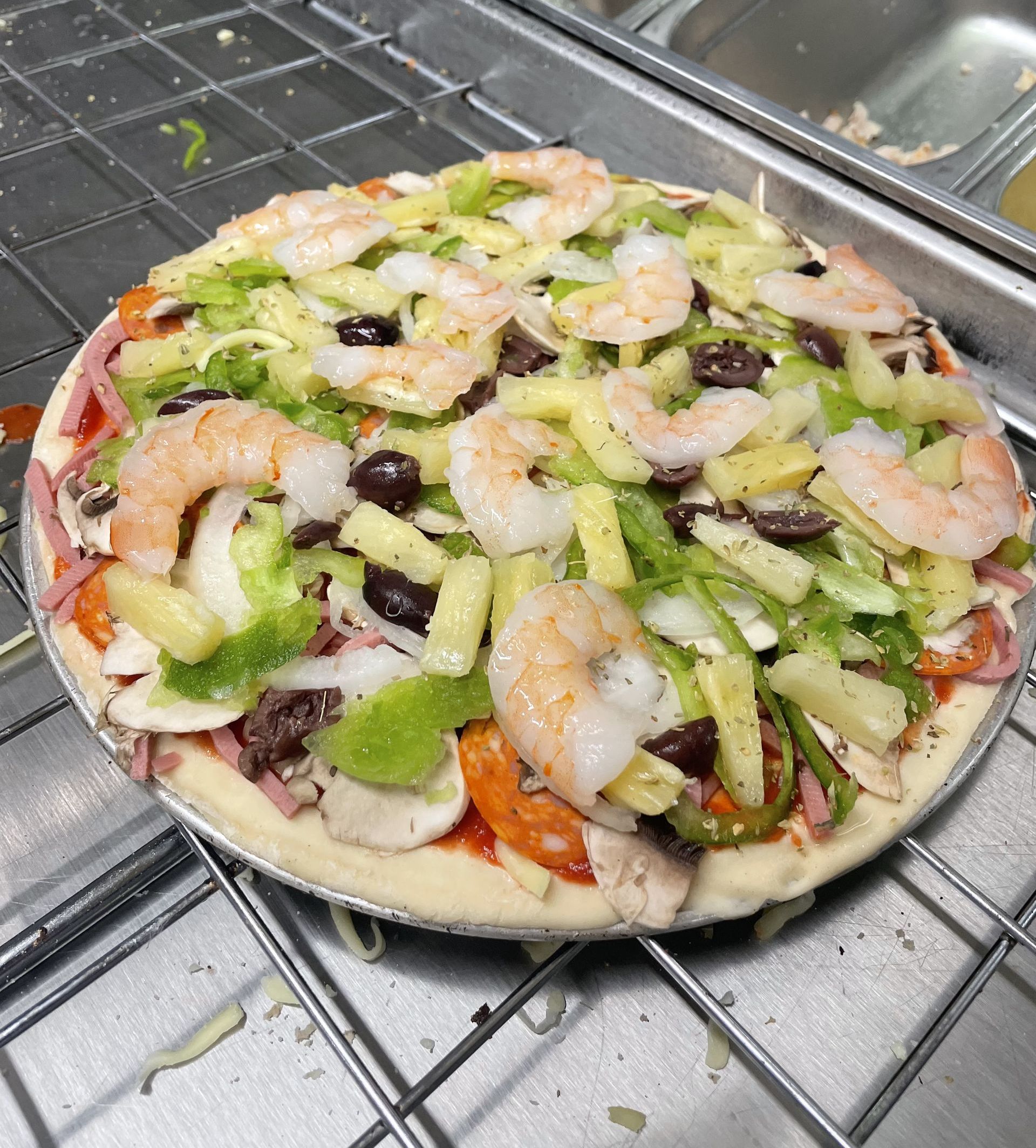 A Pizza And A Glass Of Wine Are On A Wooden Table — Bel-Air Pizza In Port Macquarie, NSW
