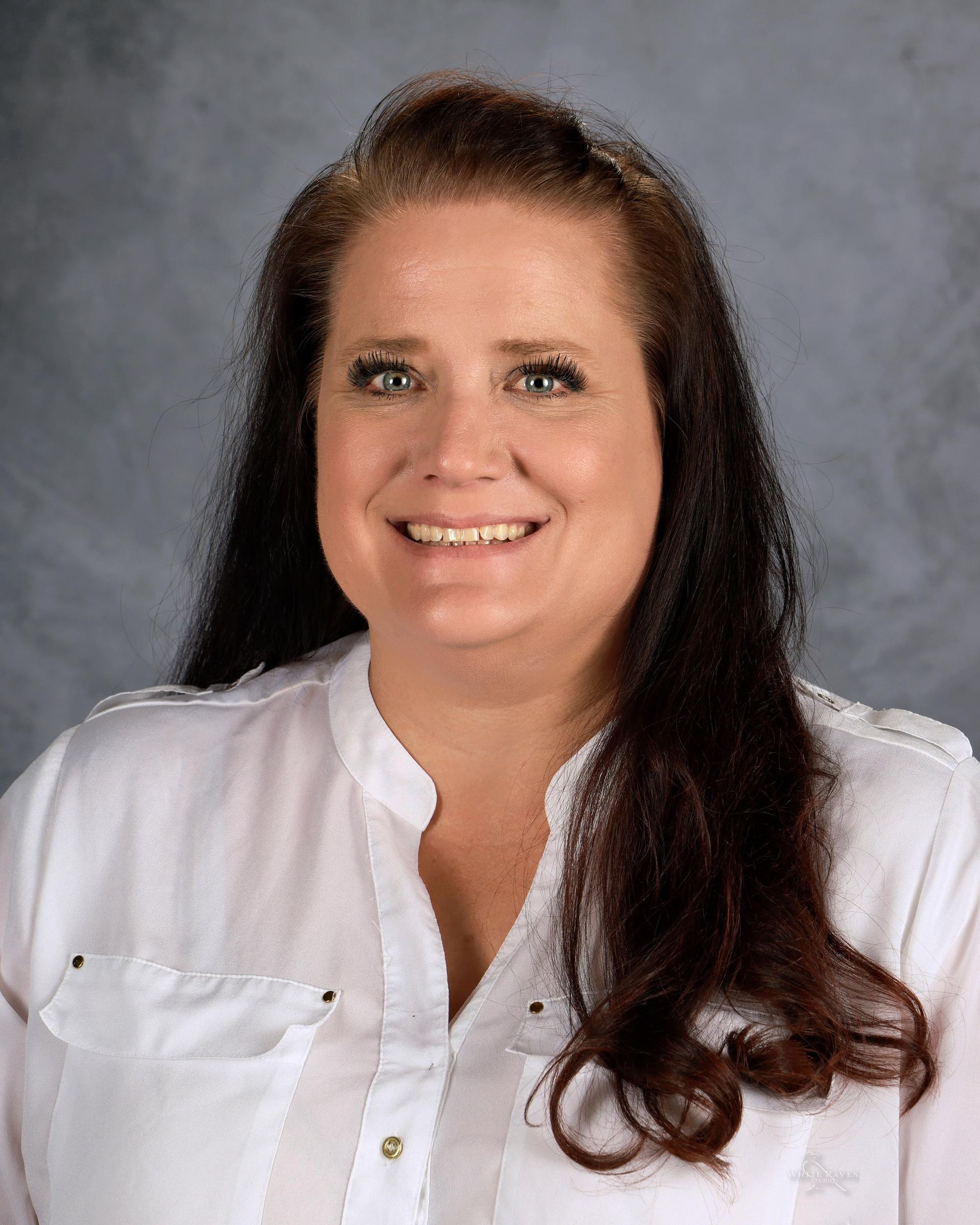 A woman in a floral shirt is smiling for a picture.