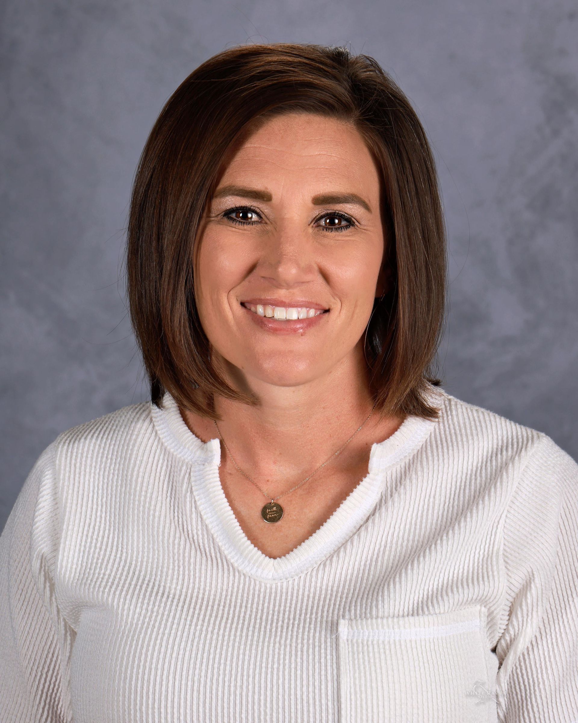 A woman in a white sweater is smiling for the camera.