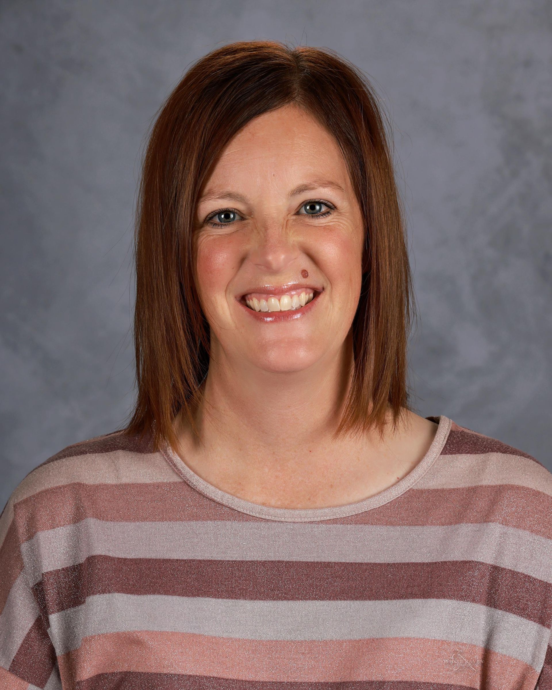A woman in a floral shirt is smiling for a picture.