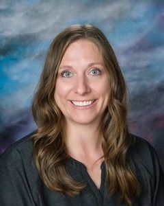 A woman is smiling for a picture in front of a blue background.
