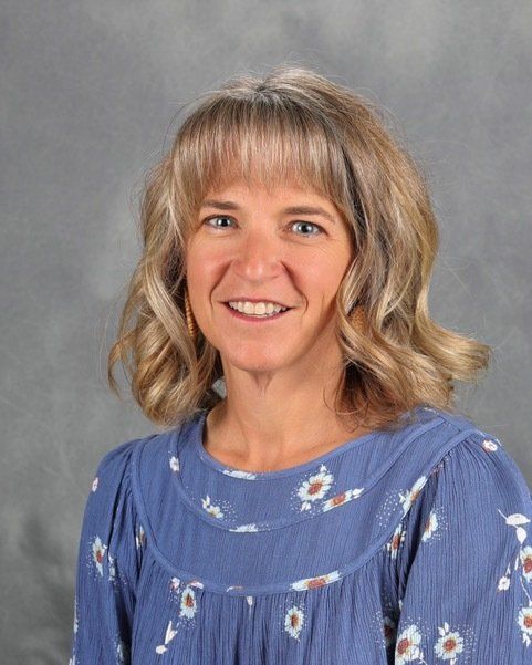A woman in a blue dress is smiling for the camera.