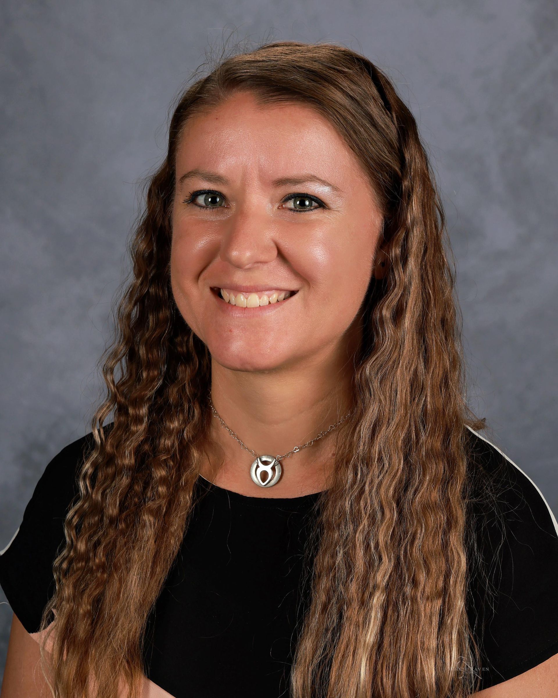 A woman with long brown hair is smiling for a picture.