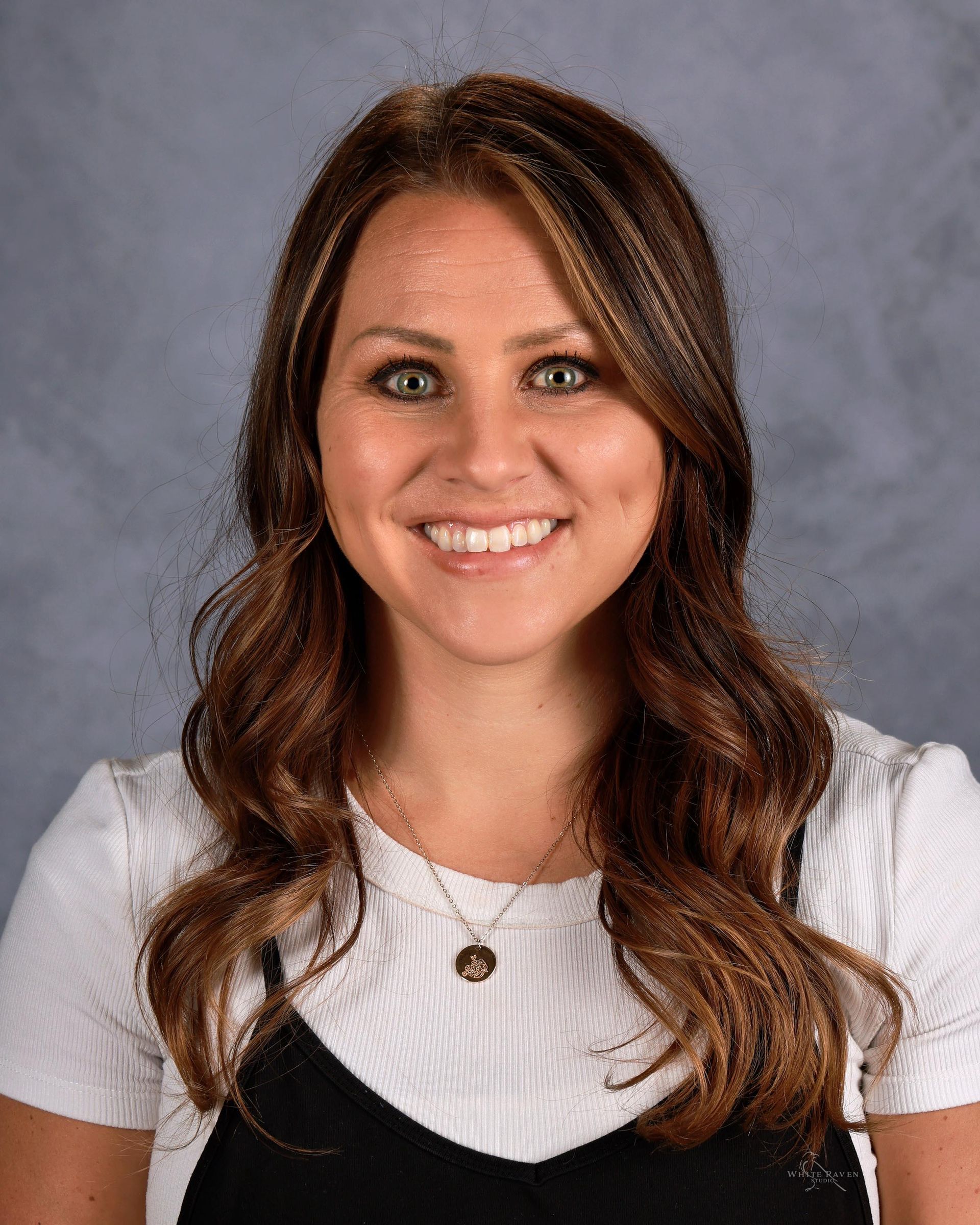 A woman wearing a pink cardigan and a blue shirt is smiling for a picture.