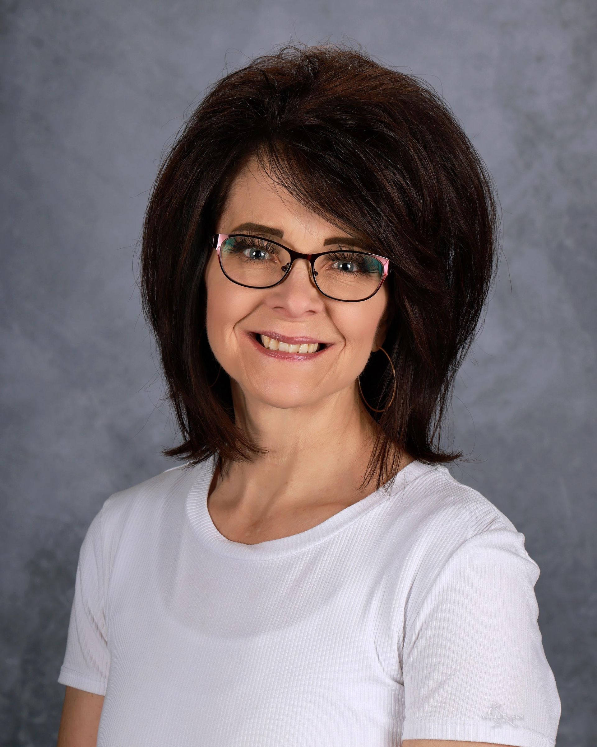 A woman wearing glasses and a blue sweater is posing for a picture.
