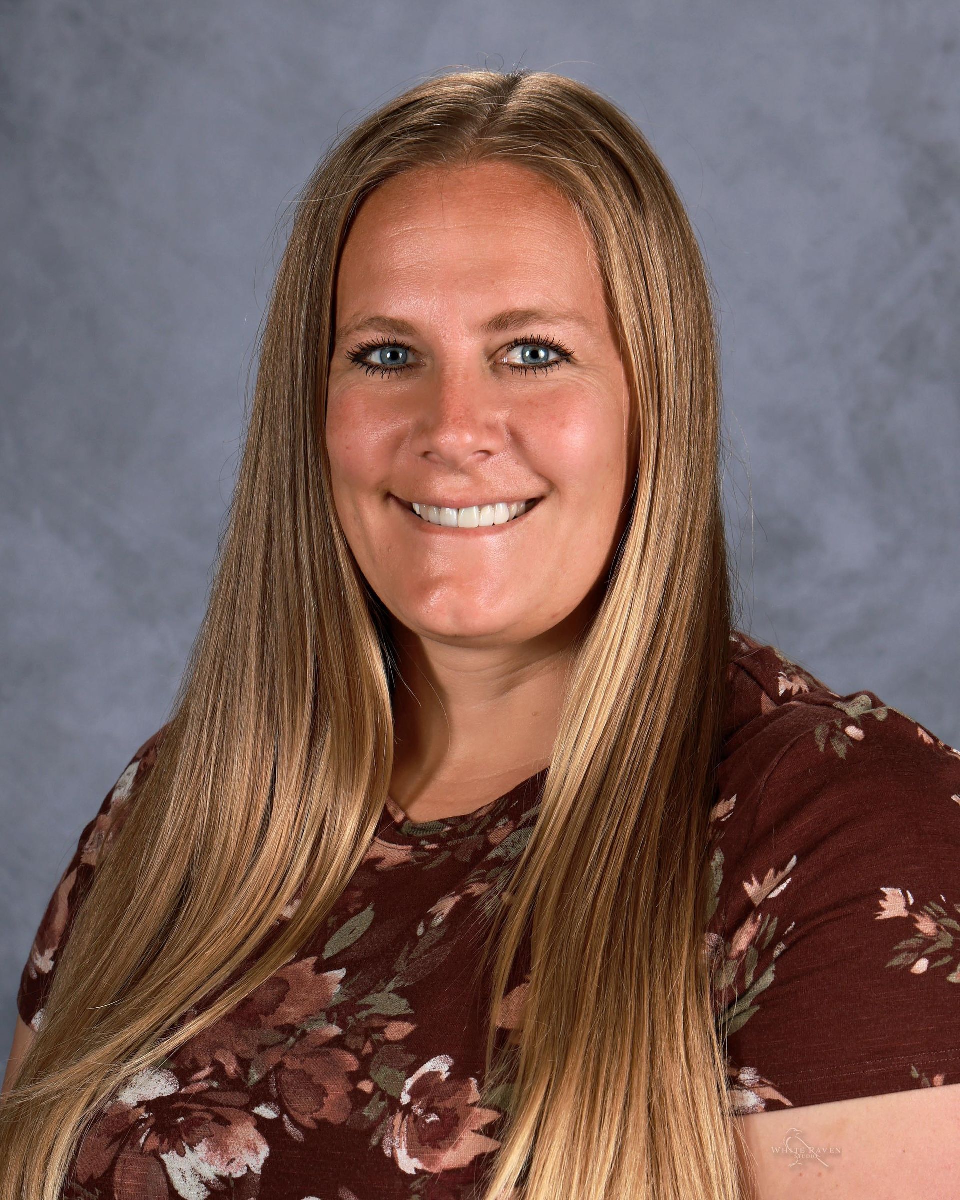 A woman in a pink shirt is smiling for a picture.