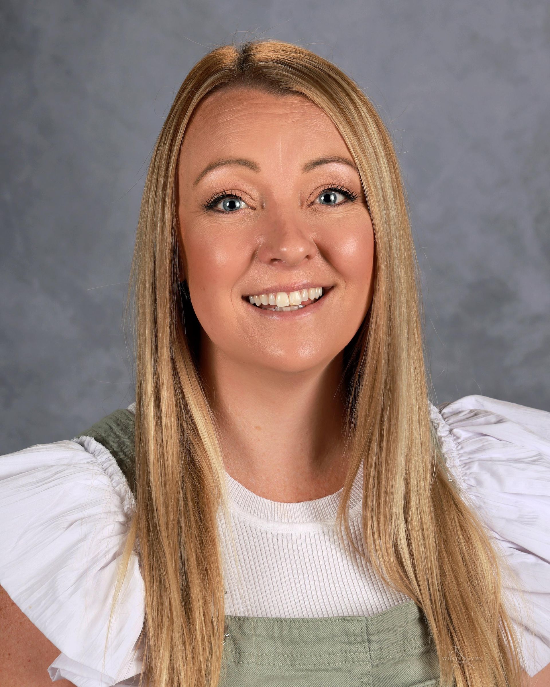 A woman in a gray sweater is smiling for the camera.