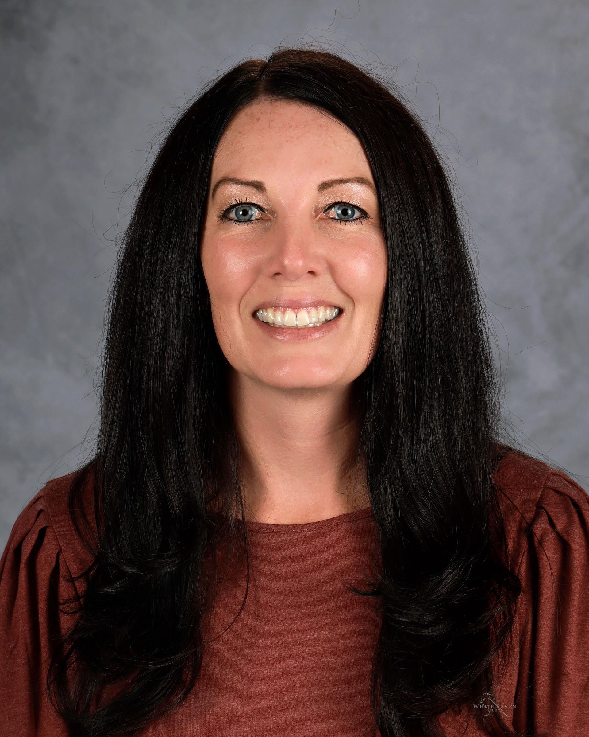 A woman in a green sweater is smiling for the camera.