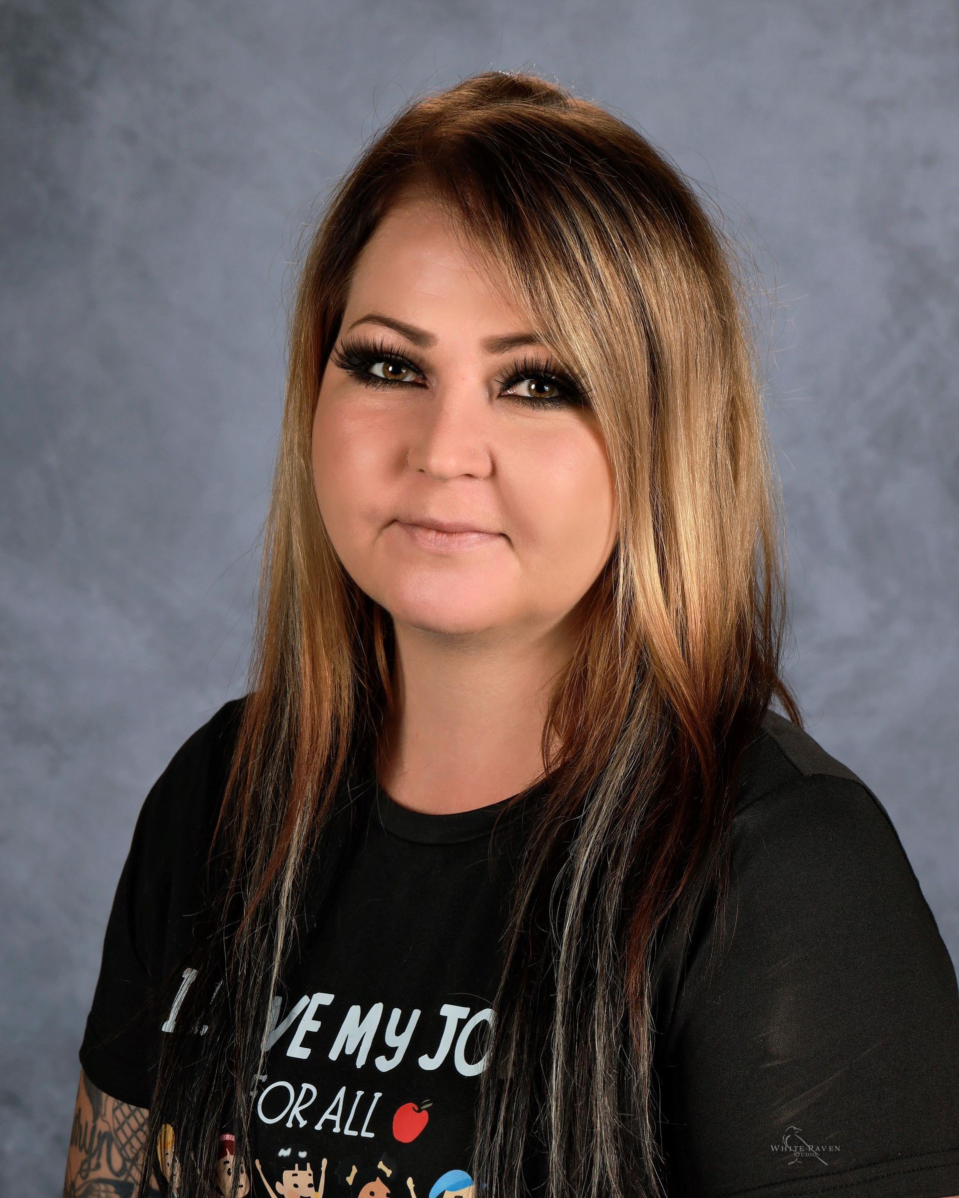 A woman with long dark hair is wearing a white shirt with black embroidery on the sleeves.