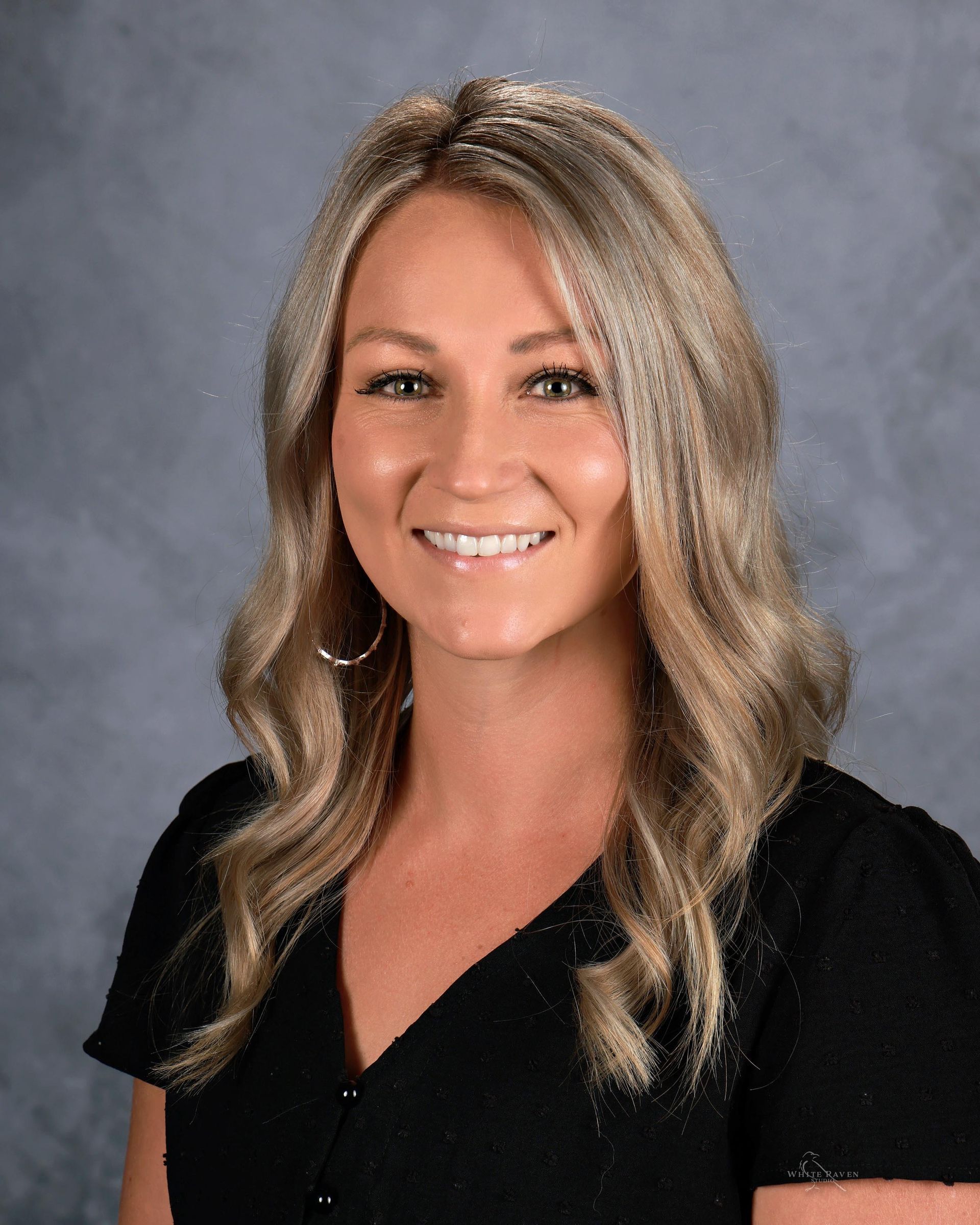 A woman in a white shirt is smiling for the camera.
