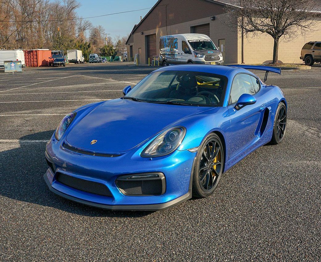A blue porsche 911 gt4 is parked in a parking lot.