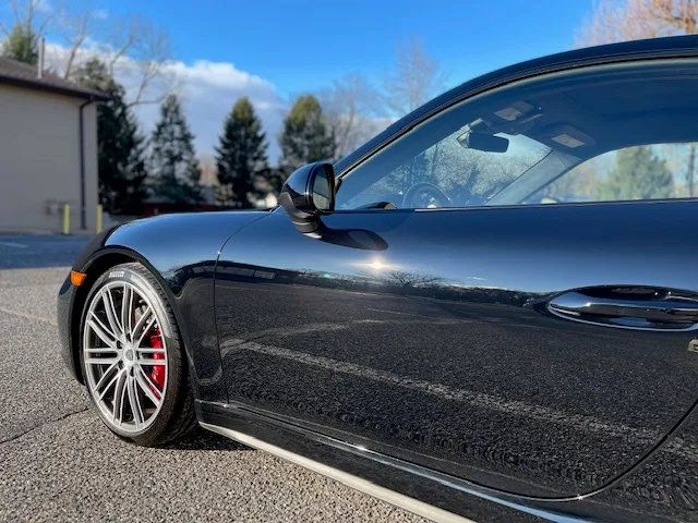 Black Porsche 911 with ceramic coating applied, showcasing mirror-like gloss finish and reflective p