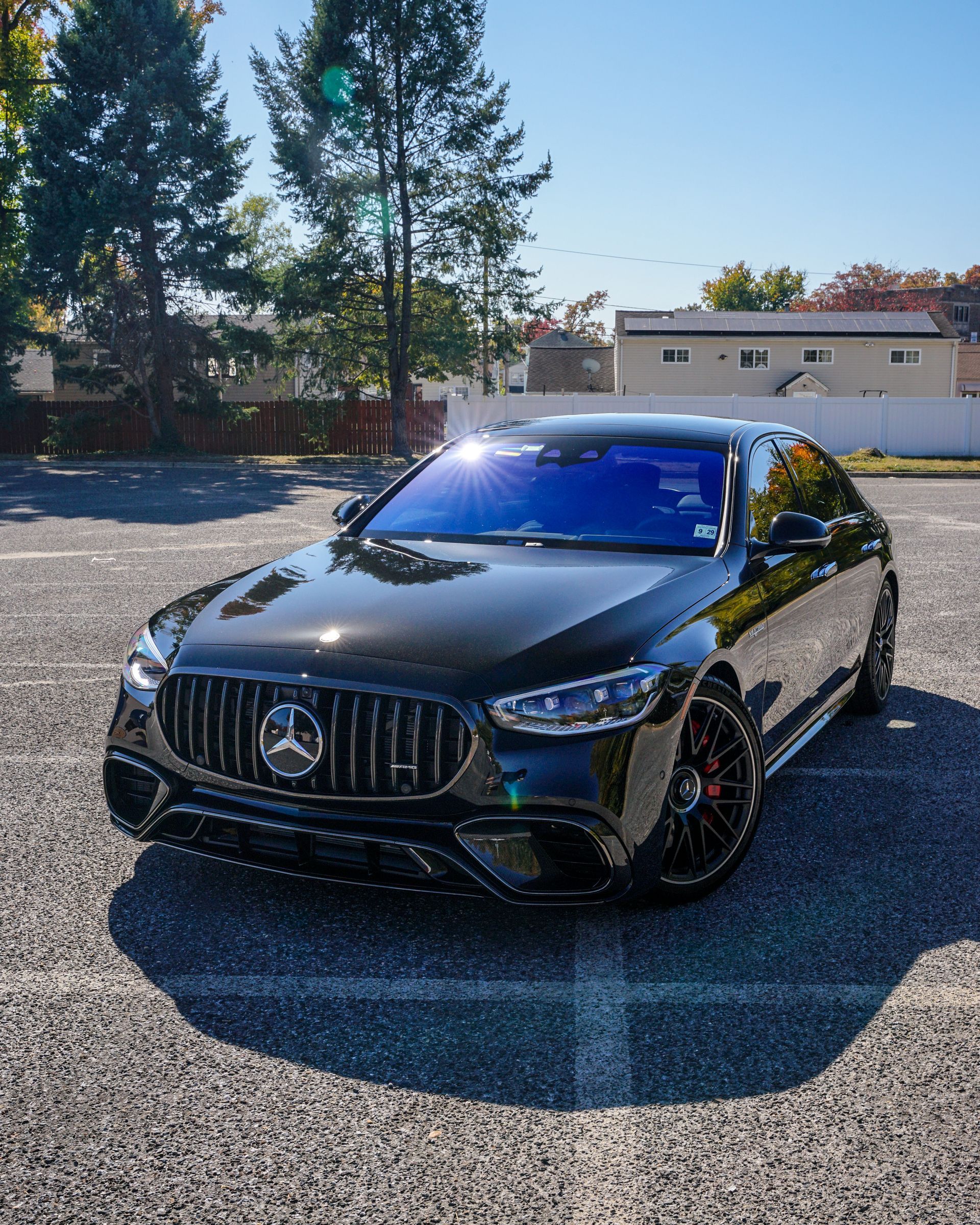 A black mercedes benz is parked in a parking lot.