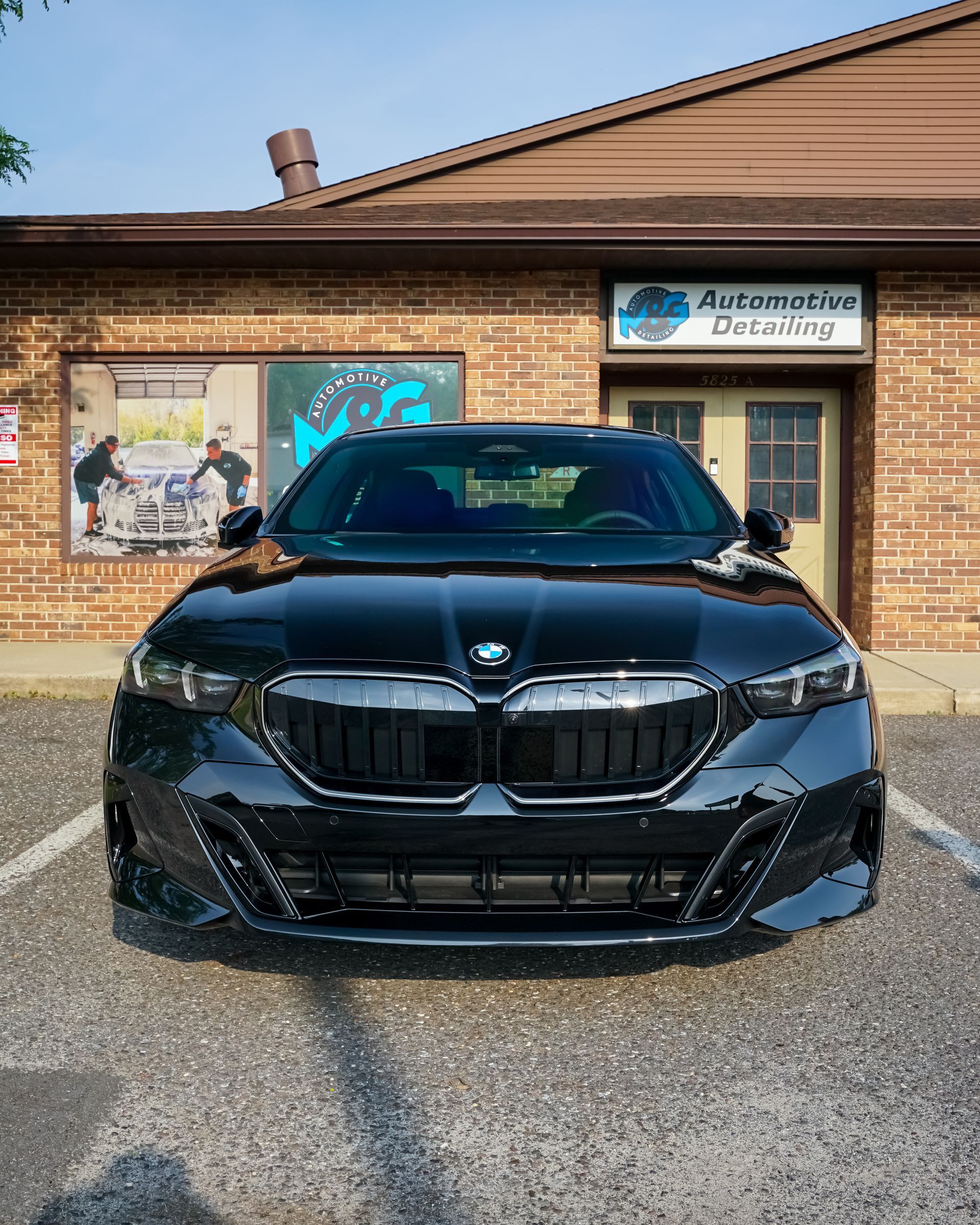 Black BMW sedan parked in front of a brick building with