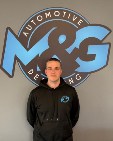 Man in black hoodie stands in front of a blue and black 