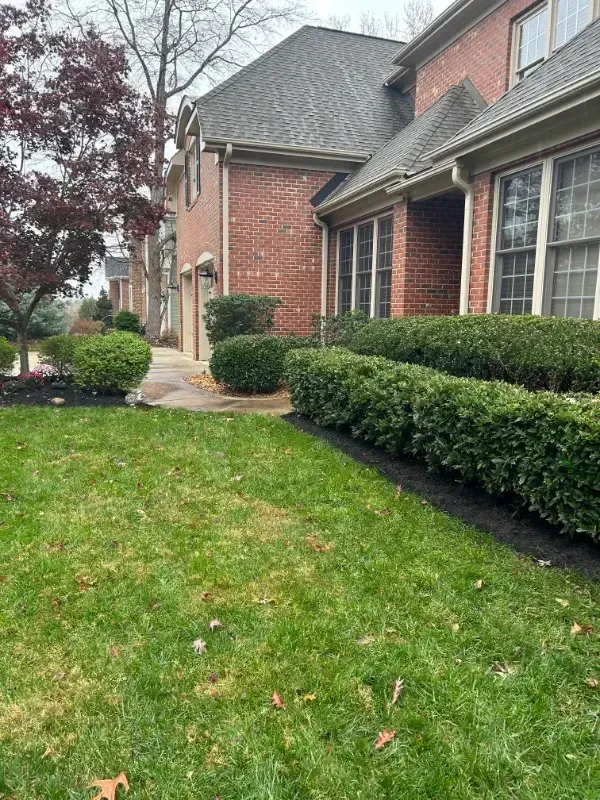 A large brick house with a lush green lawn in front of it.