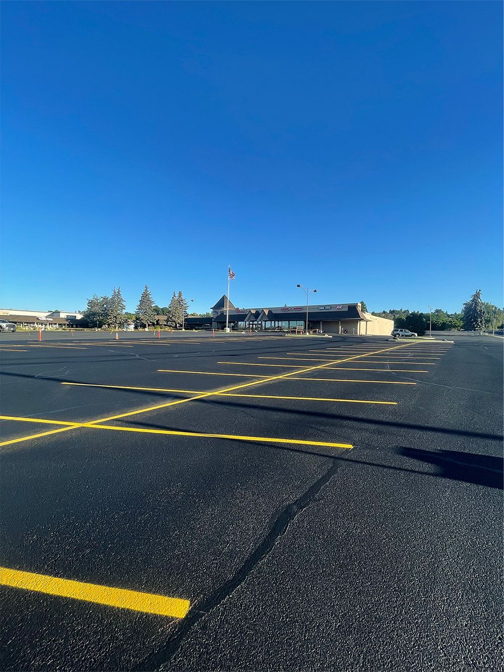 A parking lot with yellow lines and a building in the background