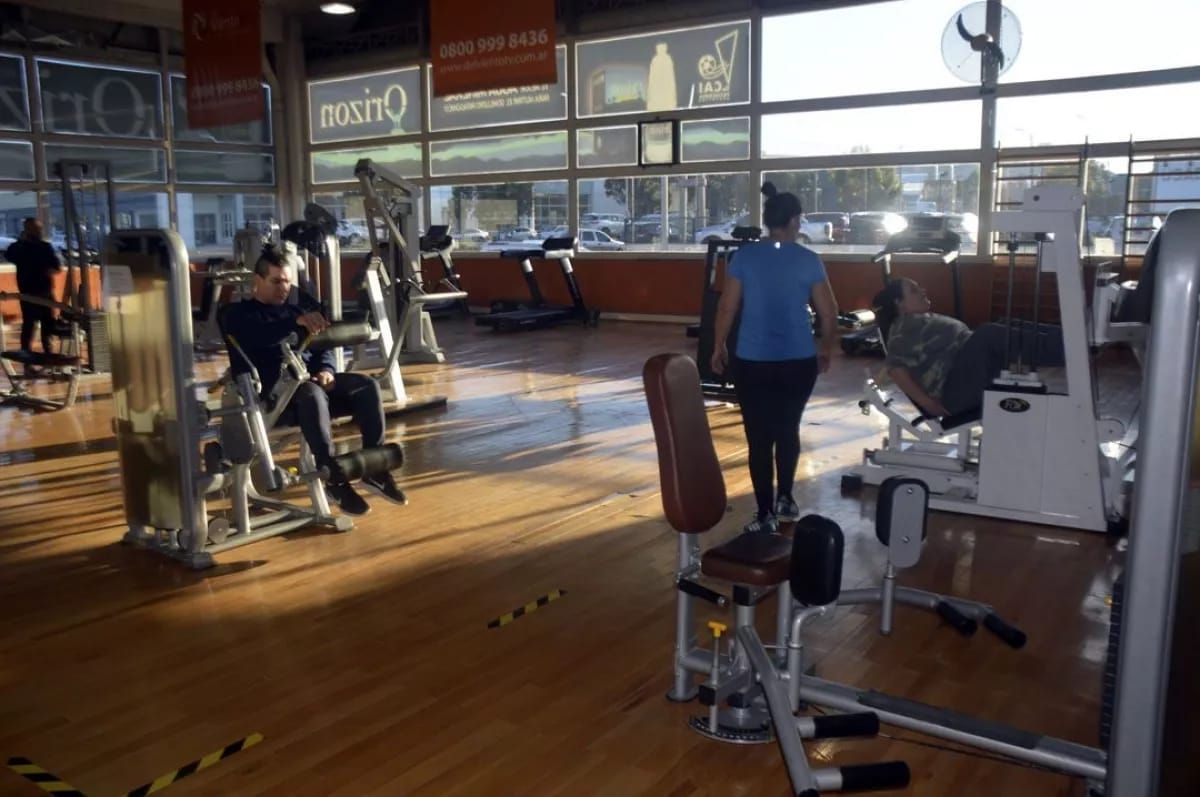 Una mujer camina por un gimnasio lleno de equipos de ejercicio.