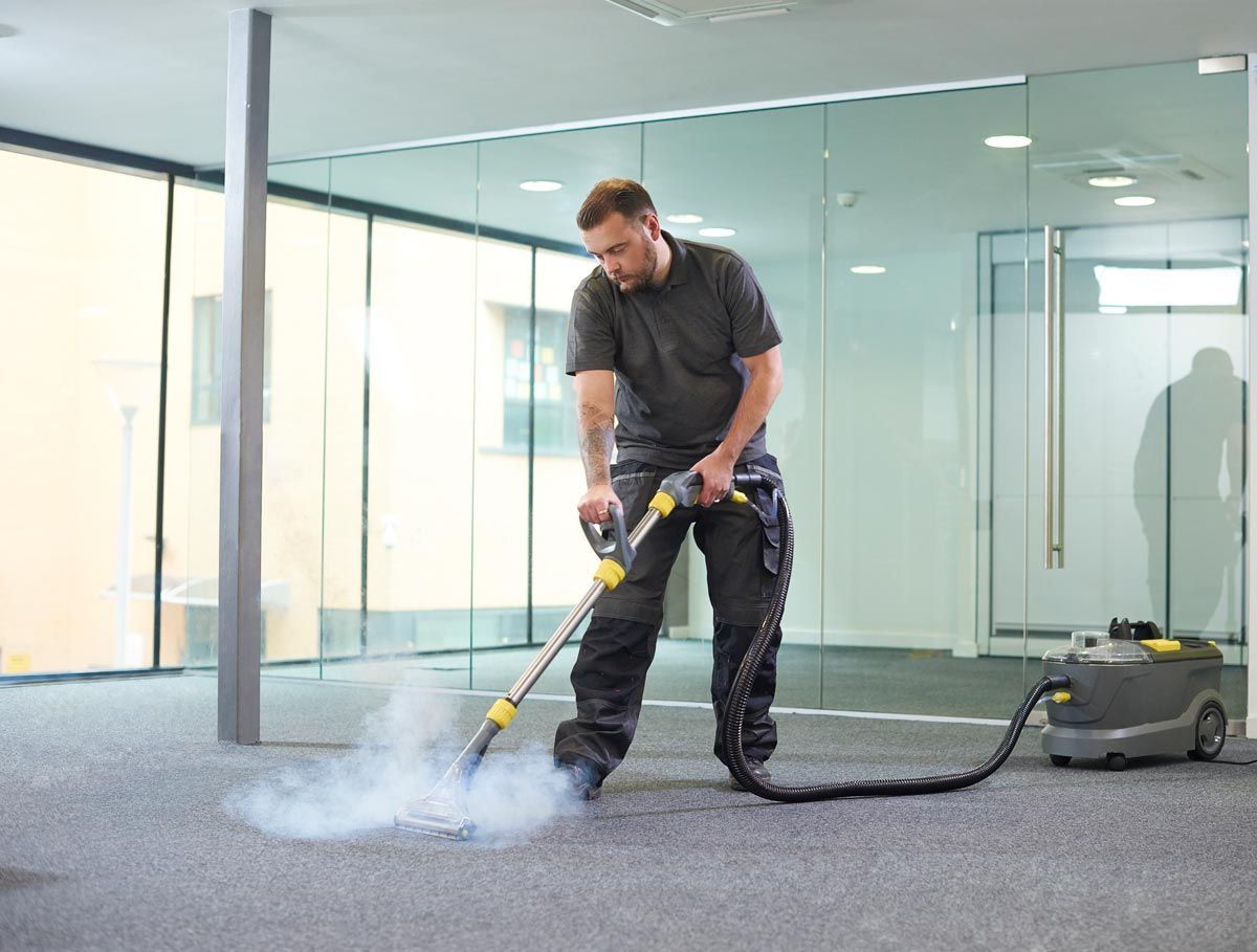 A man is using a vacuum cleaner to clean a carpet in an office.