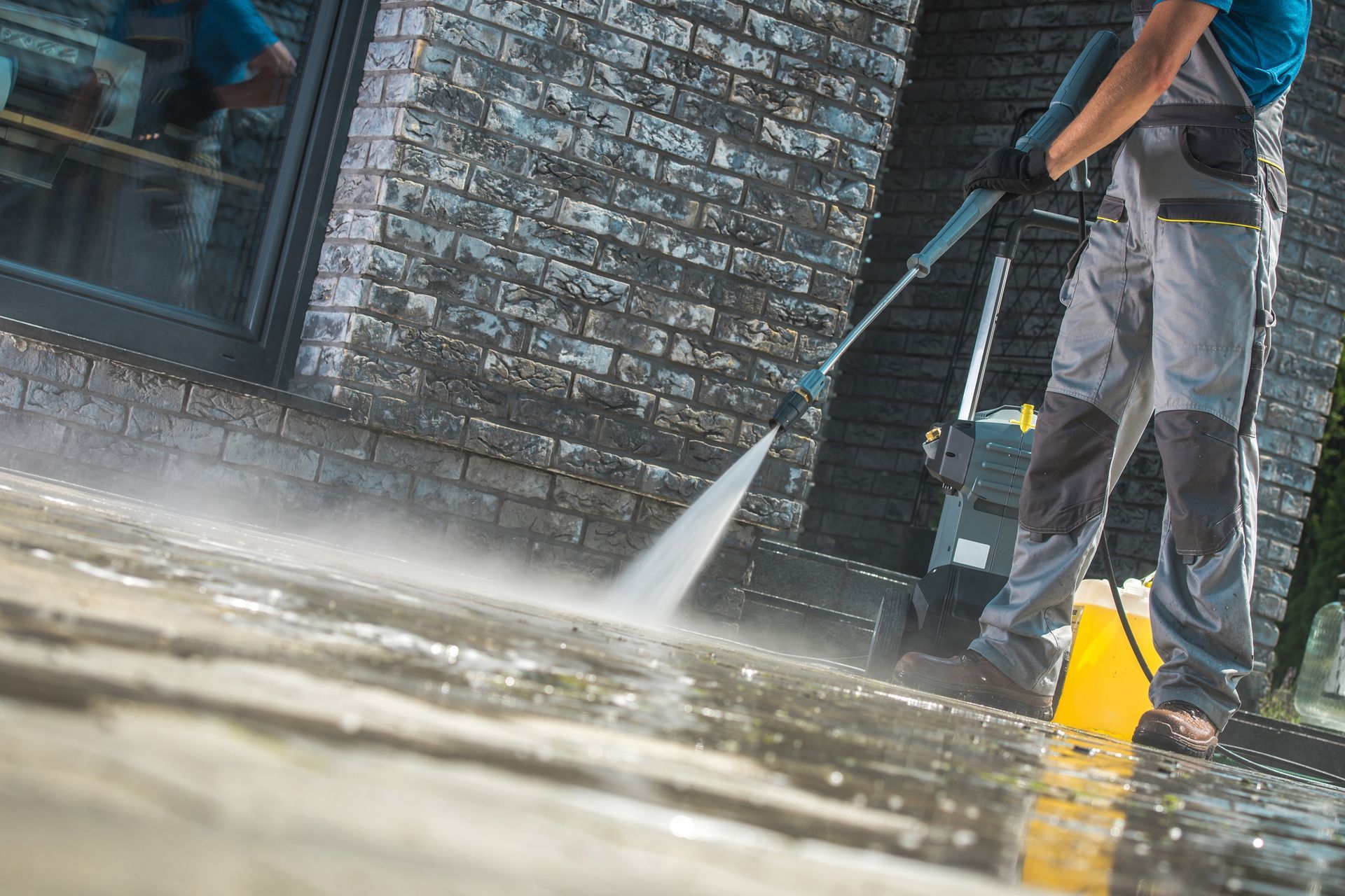 A person is using a pressure washer to clean the side of a house.