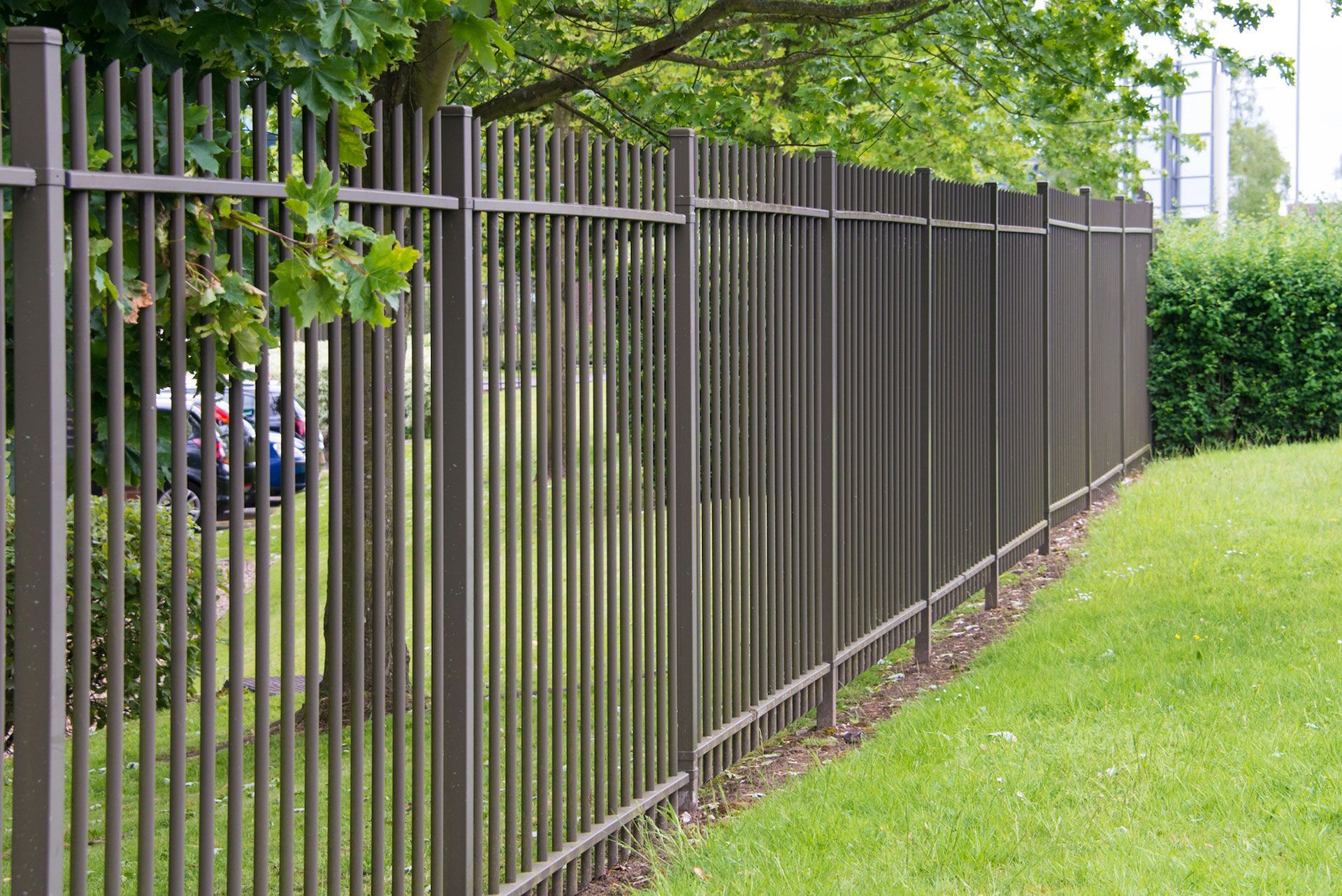 A metal fence surrounds a lush green field